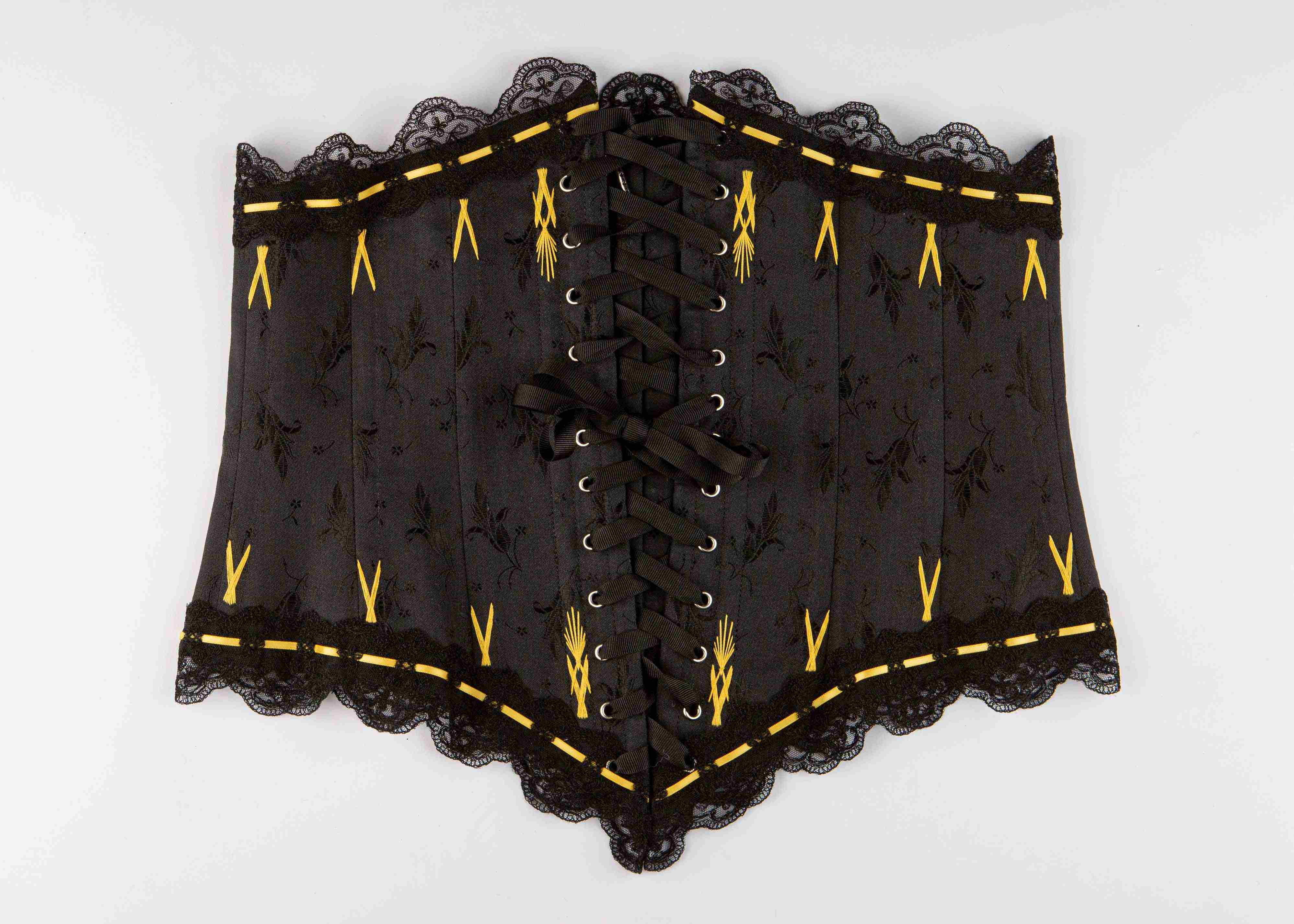 A black and yellow corset lying on a plain surface.