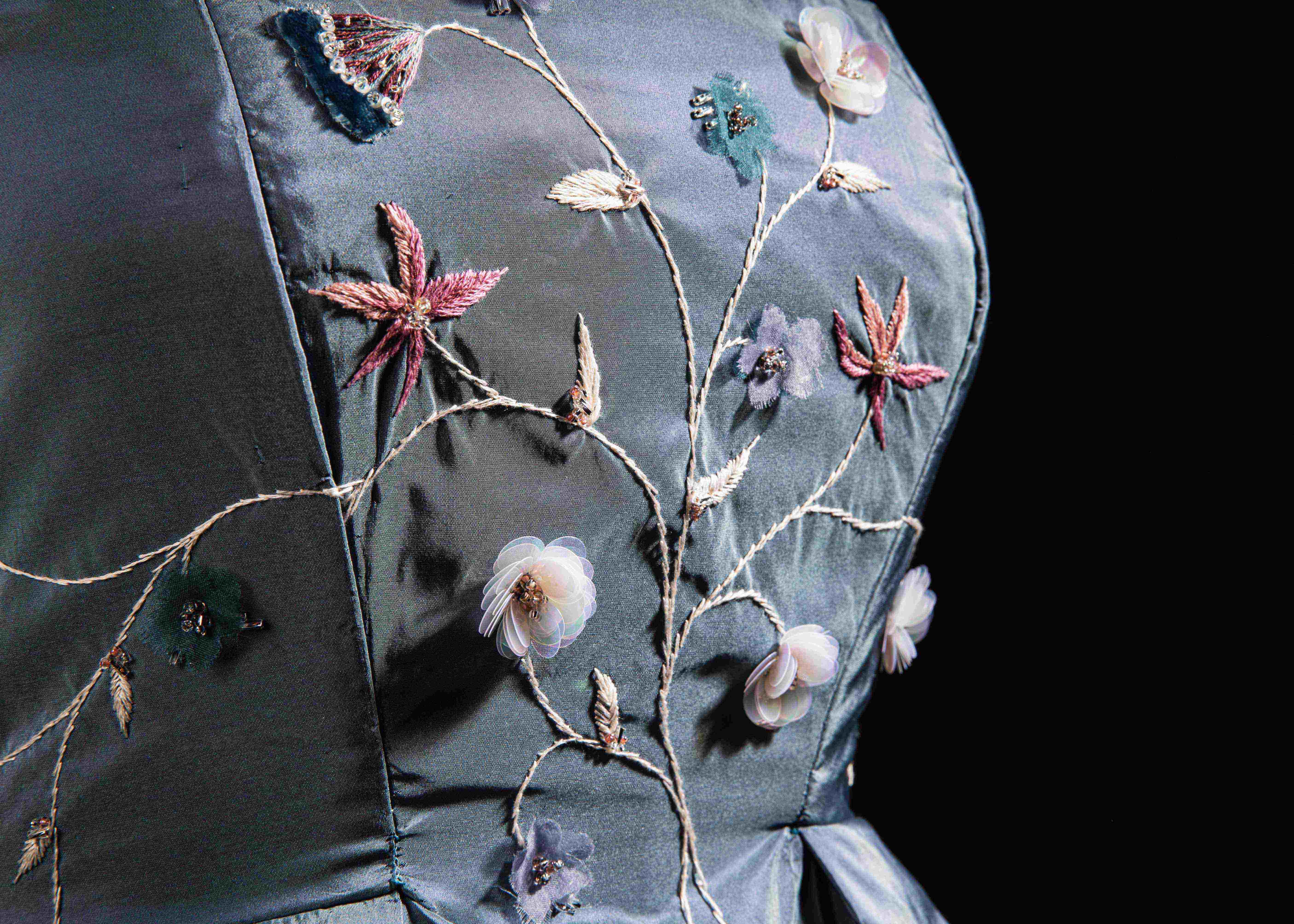 Close-up of the front of a blue dress showing floral embroidery.