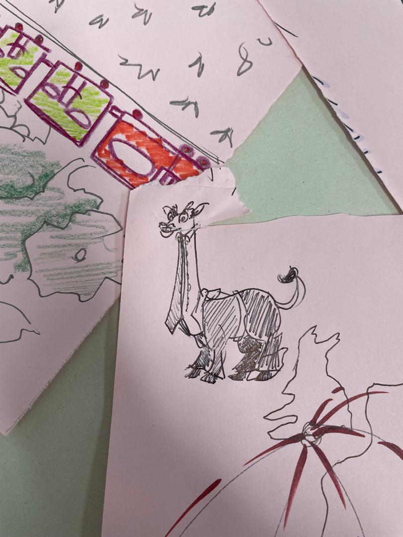 Children's drawings on white paper featuring coloured pencil sketches of animals, green geometric shapes, and scattered text elements.