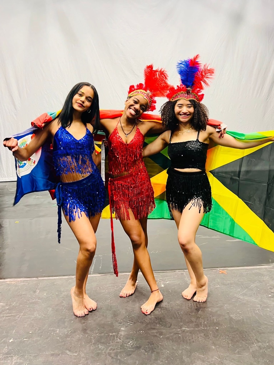Nicole Elizabeth Phillip alongside other carnival dancers holding the Jamaican flag in colourful costumes.