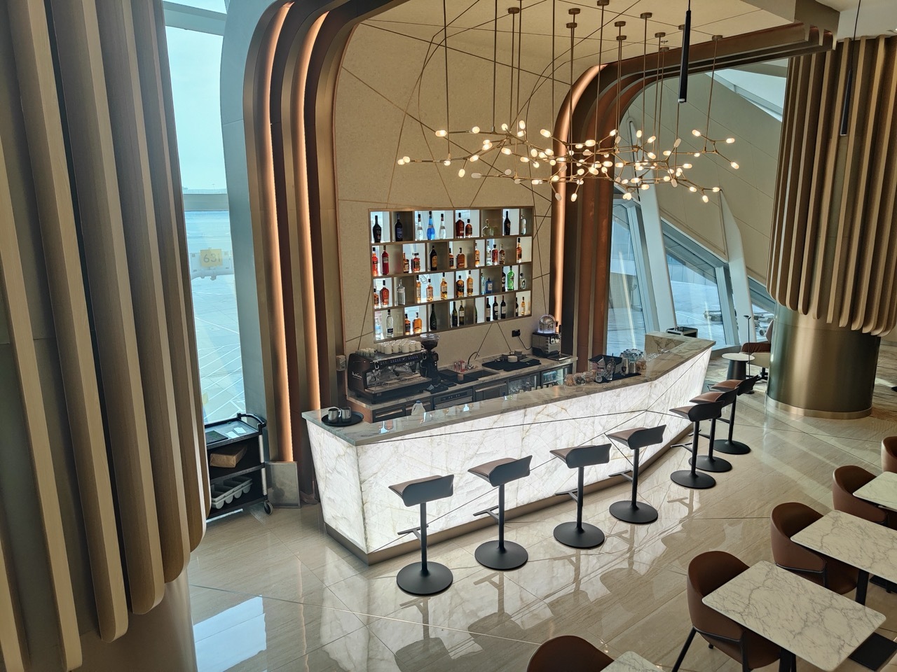 Etihad US Pre-clearance Lounge featuring a uniquely-lit bar with marble, brass fixtures and seating.