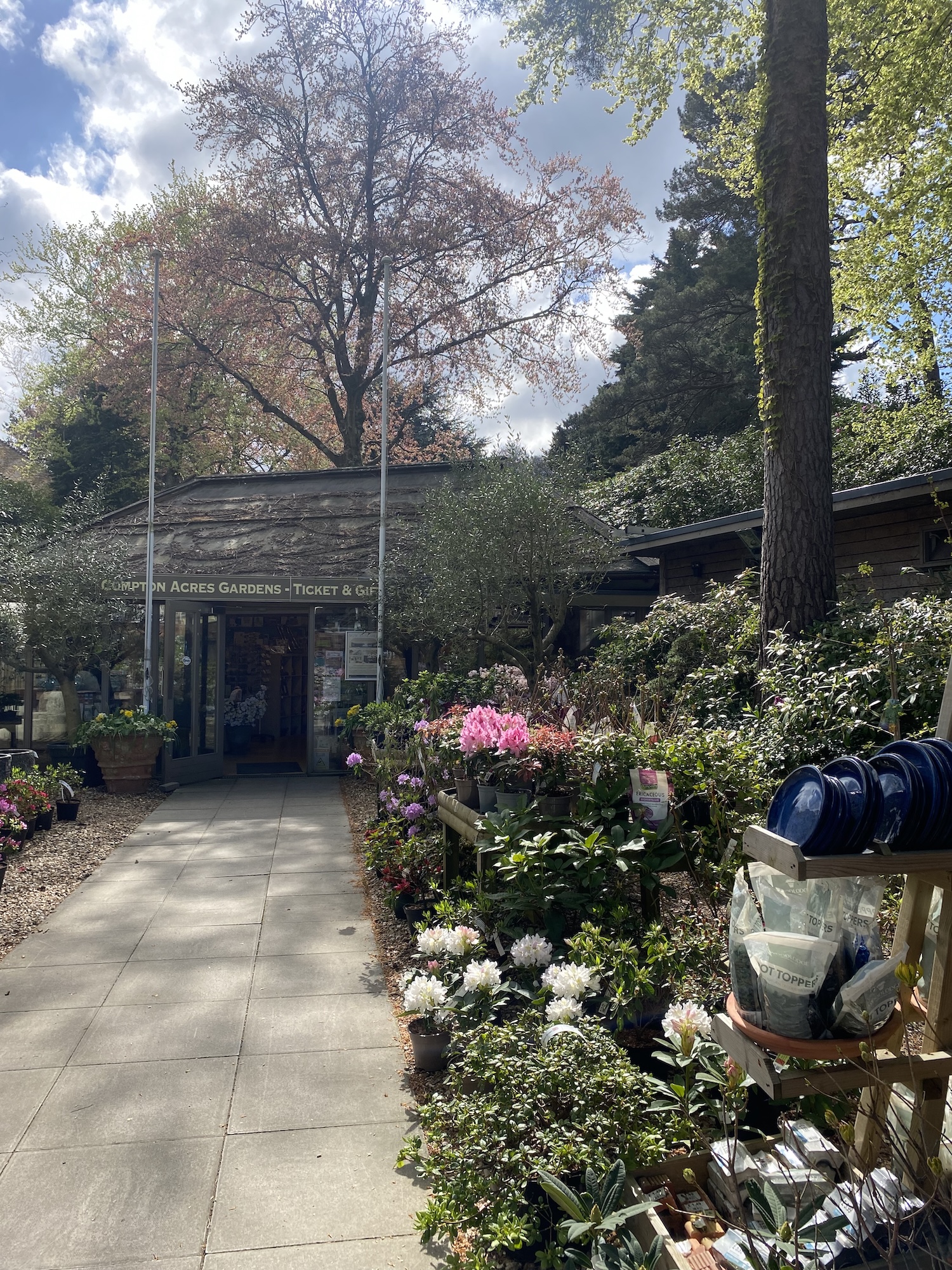 Garden centre with a large variety of potted plants on display in front of the entrance to Compton Acres, Poole.
