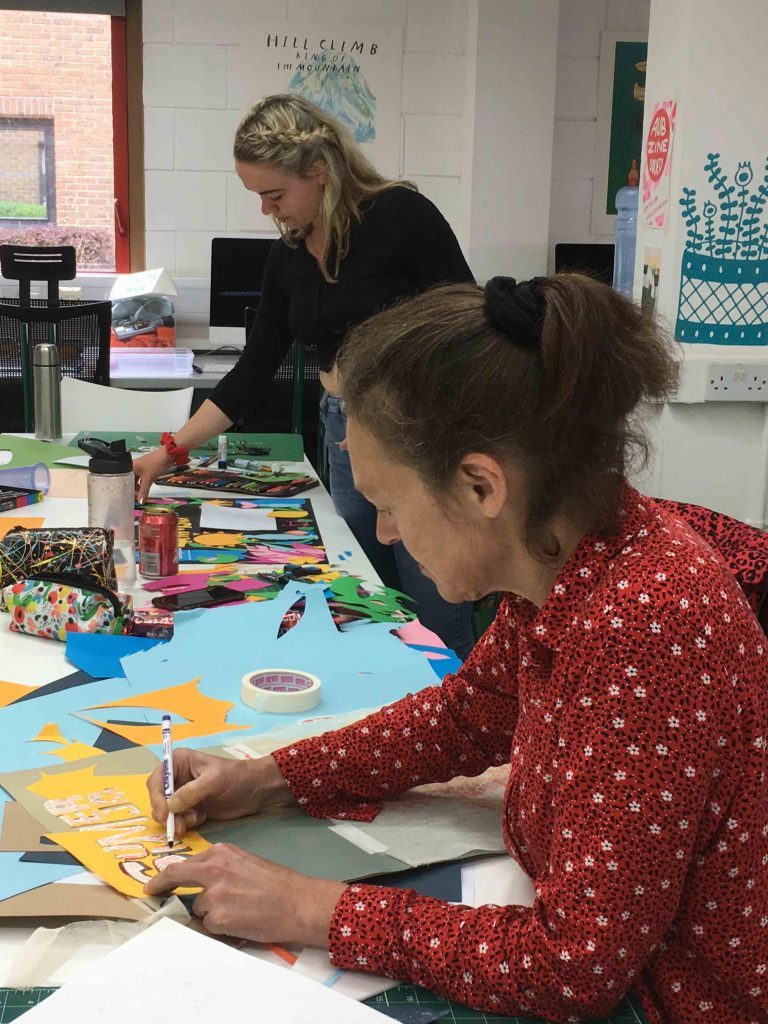 Two people working at art and craft projects at a pair of tables.