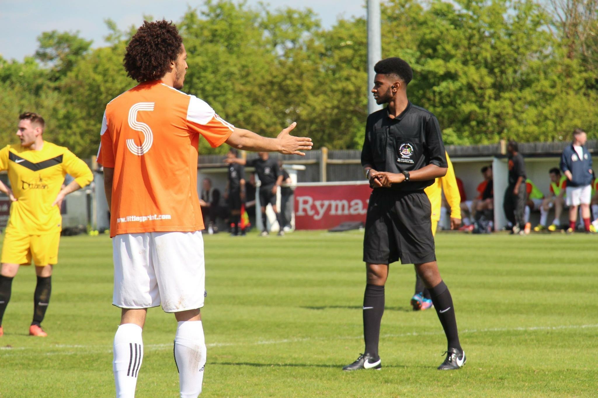 Ashley Hickson-Lovence stands in referee uniform on a football pitch