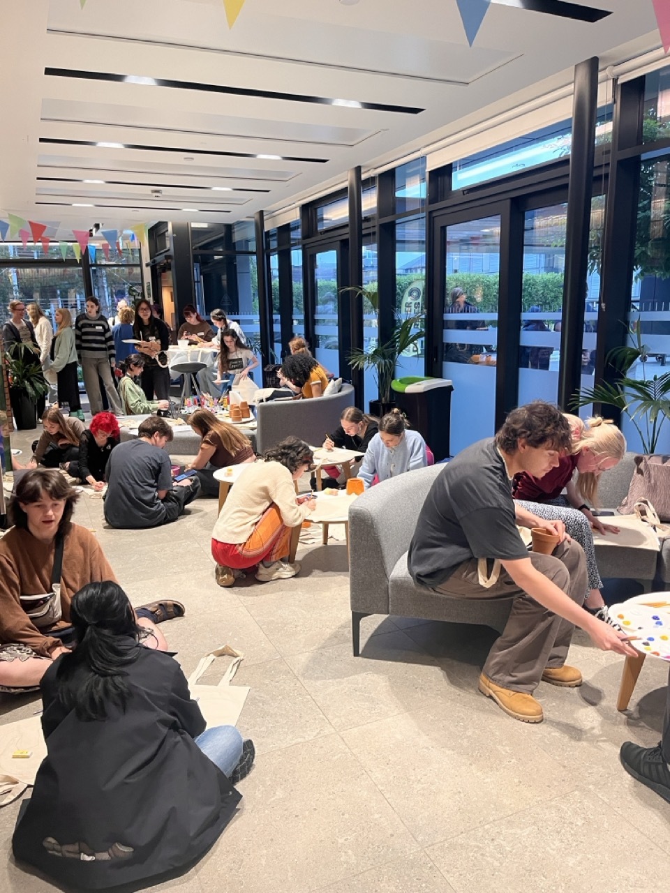 Students gathered round tables and chairs in campus halls for arts and crafts.