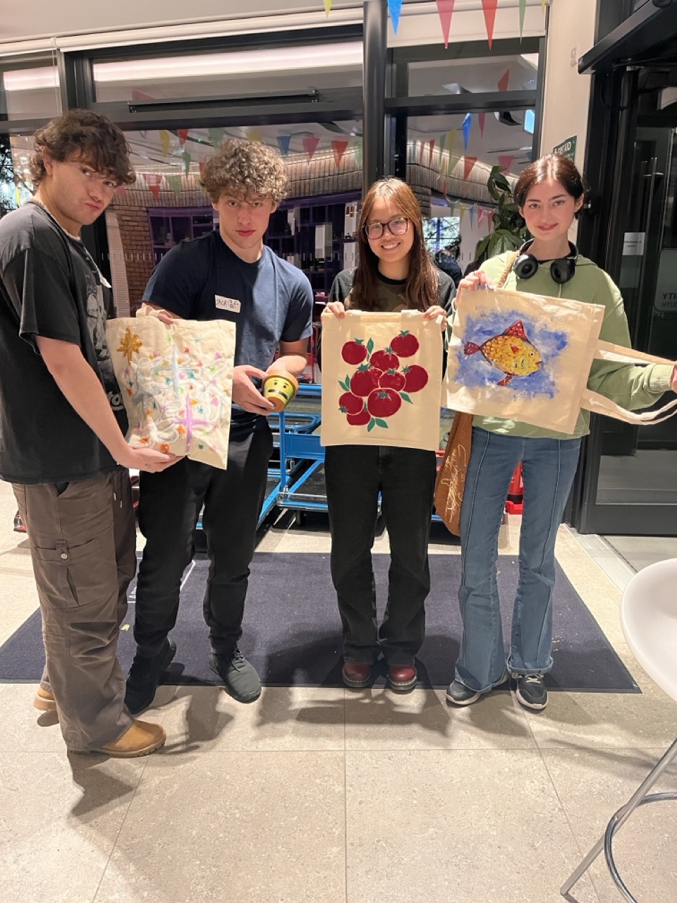 Students showing off custom-made tote bags.