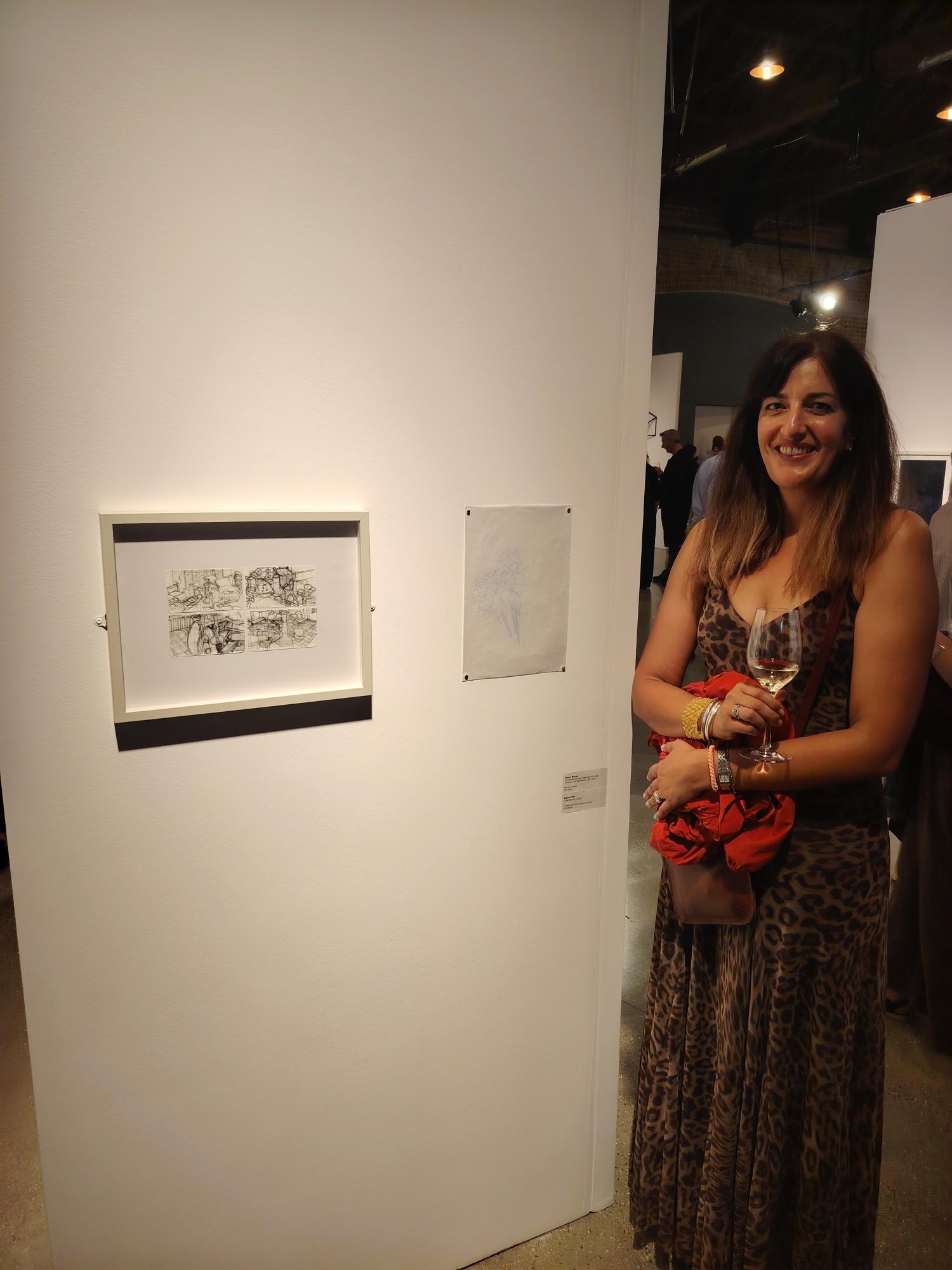 S Firth standing next to one of her drawings on display on a gallery wall for the Trinity Buoy Wharf Drawing Prize 2026.