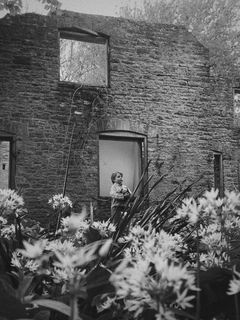 Boy standing out a run down house