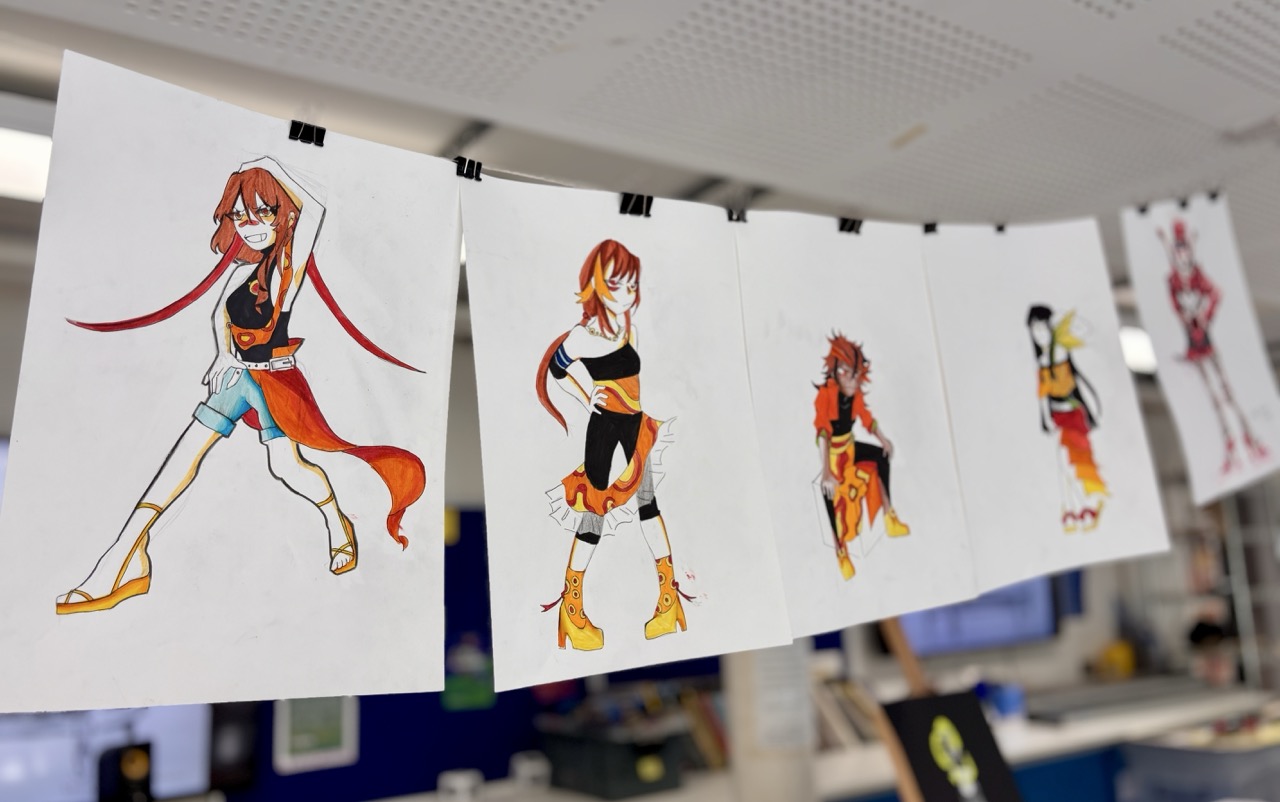 Several fashion design sketches of an illustrated woman with red hair are clipped to a line, hanging in an office or studio.