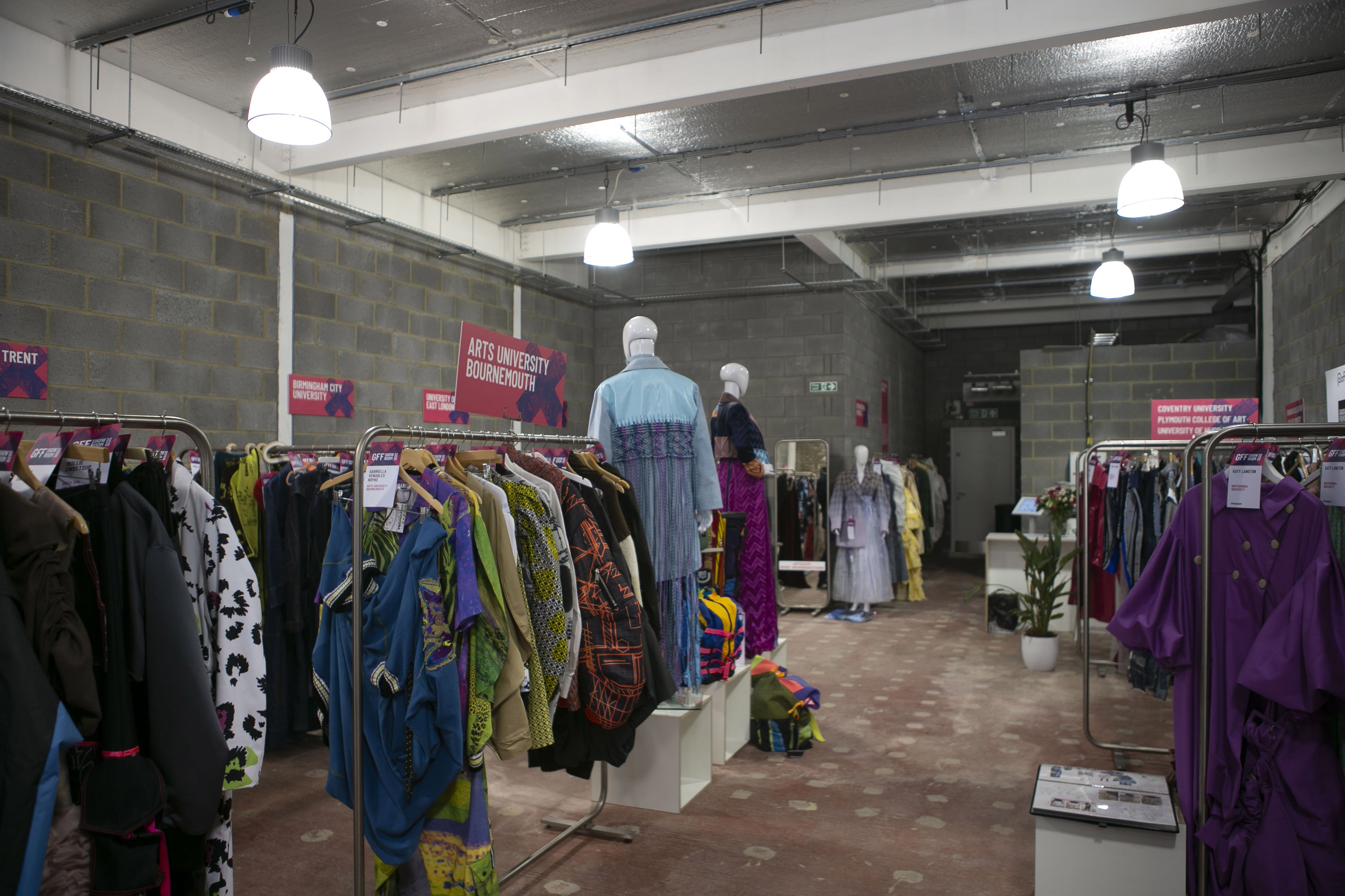A showroom space filled with mannequins and several clothes rails. A wide variety of outfits are hanging on the clothes rails.