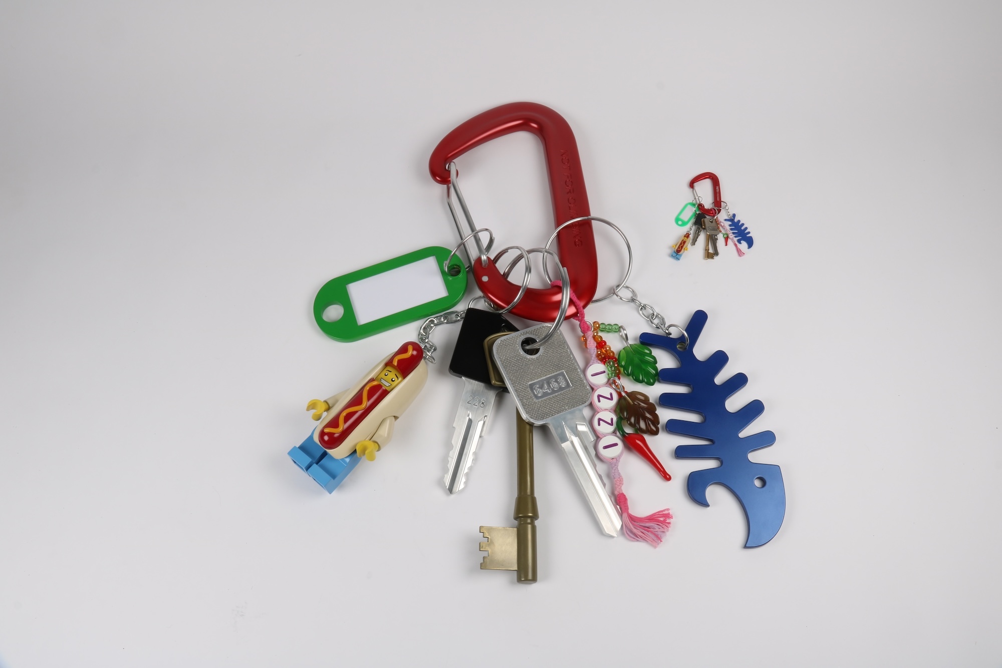 A model of a giant set of keys next to the normal-sized original set of keys, displayed on a plain white surface.