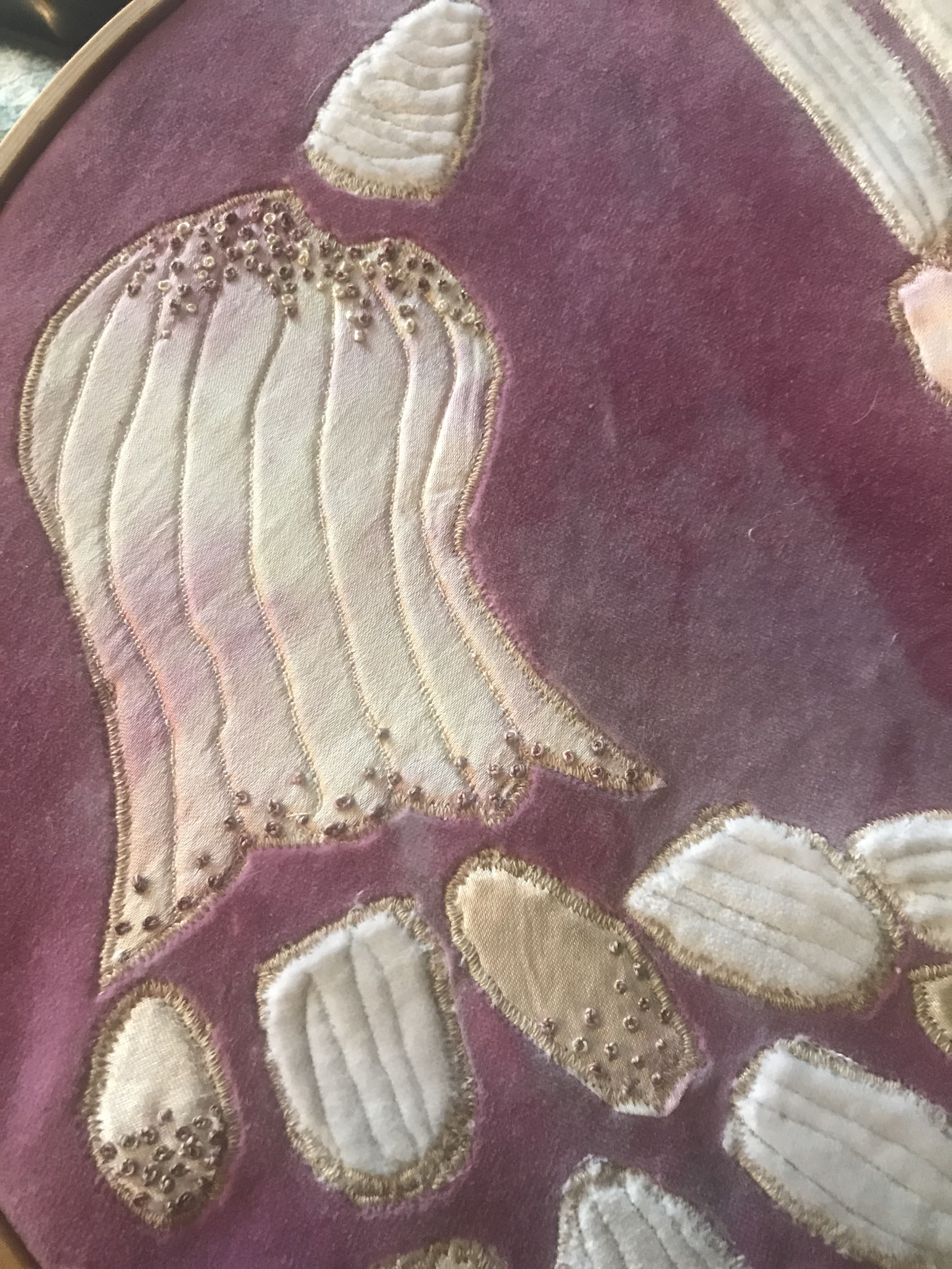 Embroidered purple fabric with white shell-shaped appliqués outlined in gold thread and decorative beading.
