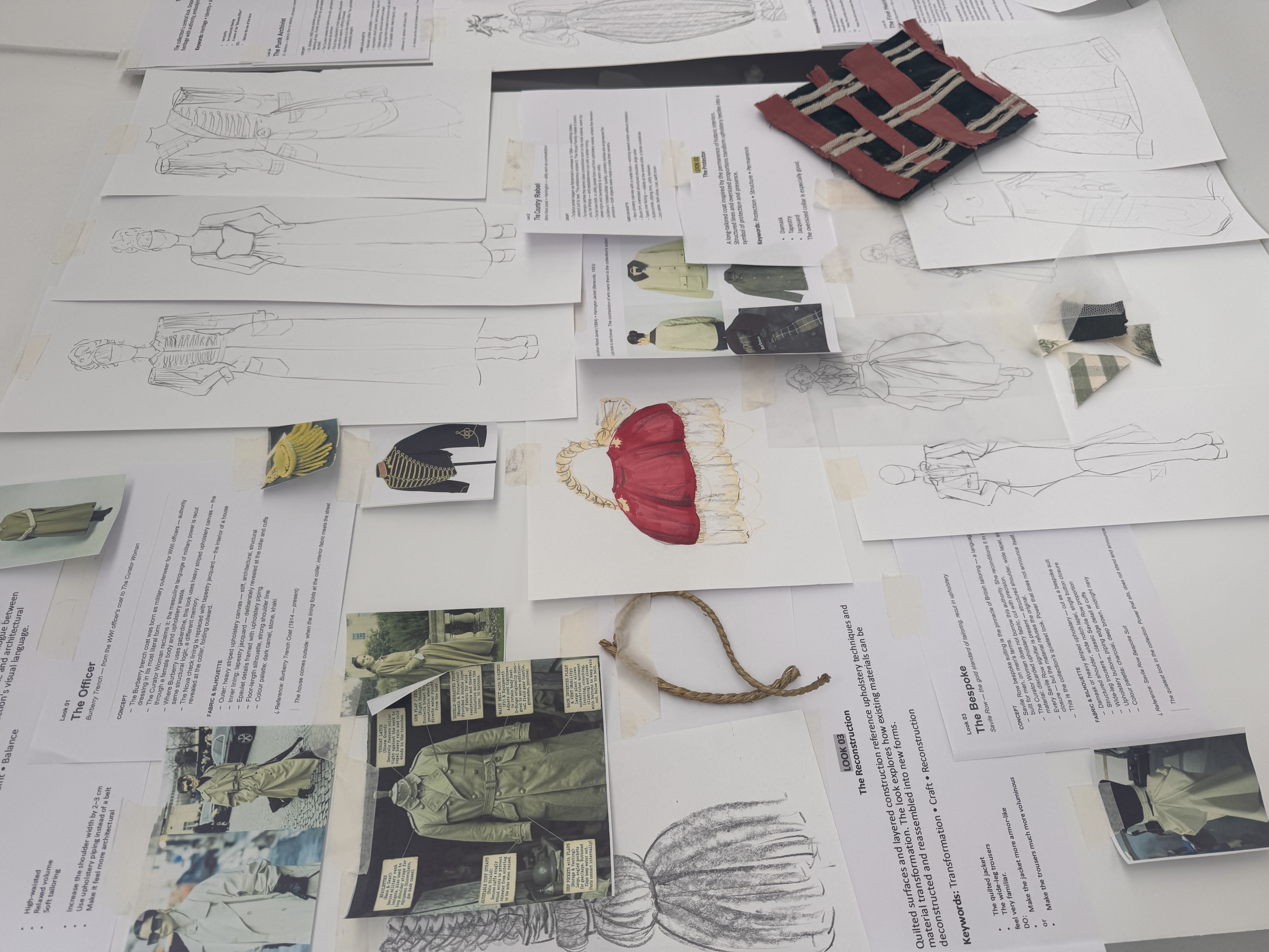 A cluttered fashion design mood board with garment sketches, printed notes and fabric swatches spread across a white table.