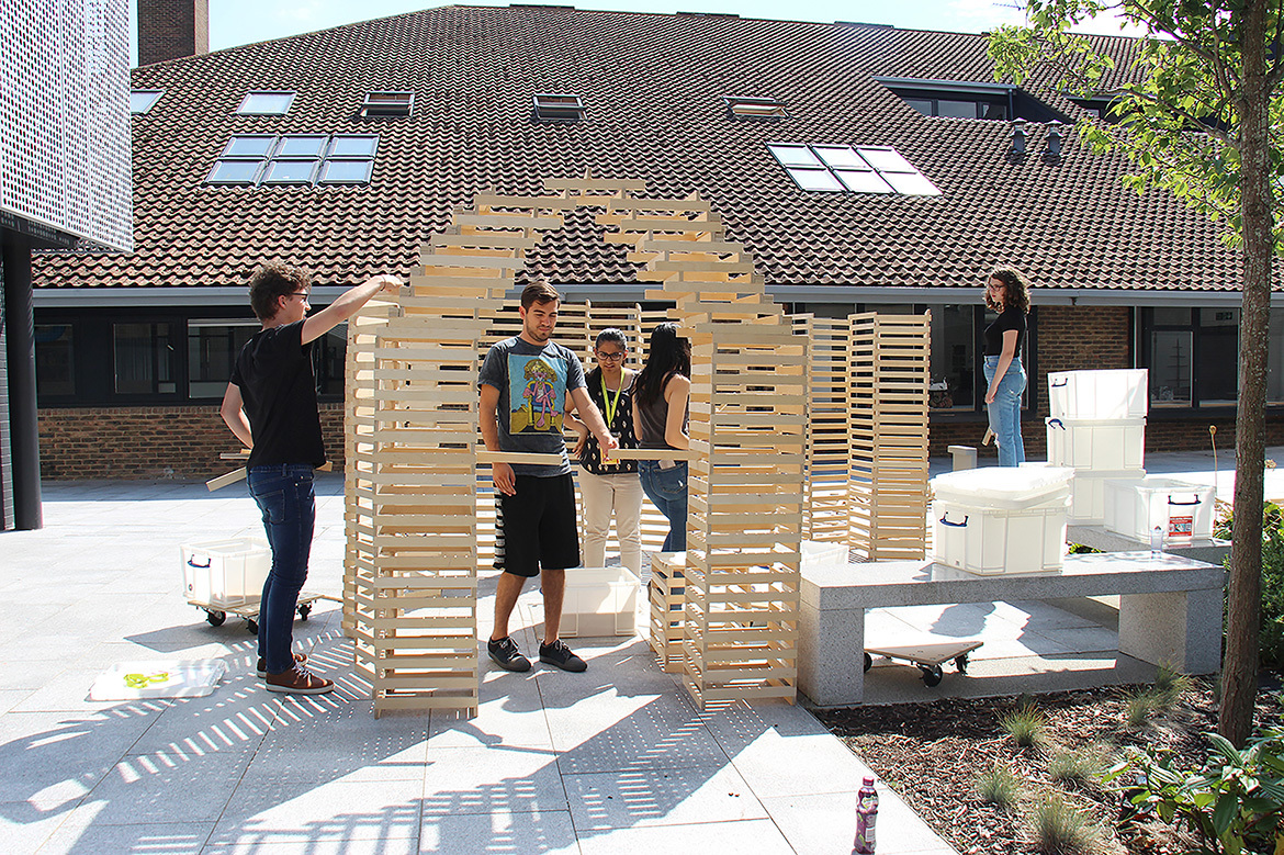 Students creating giant arch out of wood