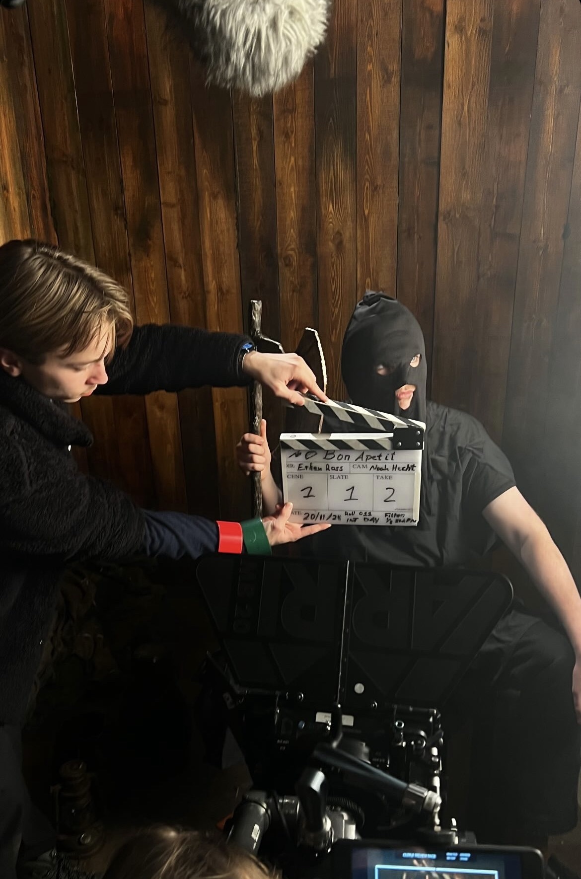 A BA (Hons) Film Production student stands holding a clapper board in front of an actor dressed like an executioner with an axe.