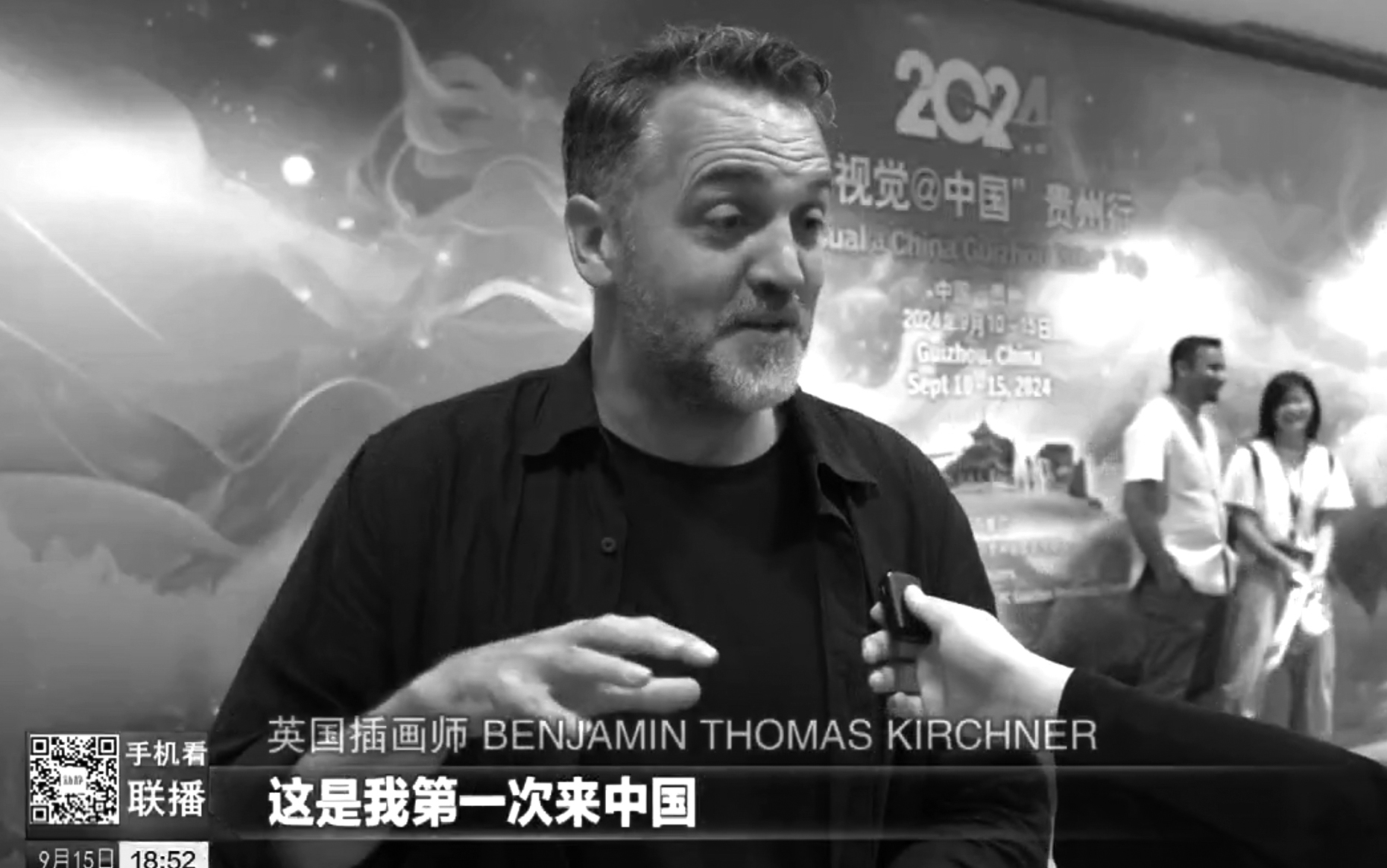 Middle-aged man in dark shirt being interviewed, with Chinese text overlay and blurred background showing people and signage.