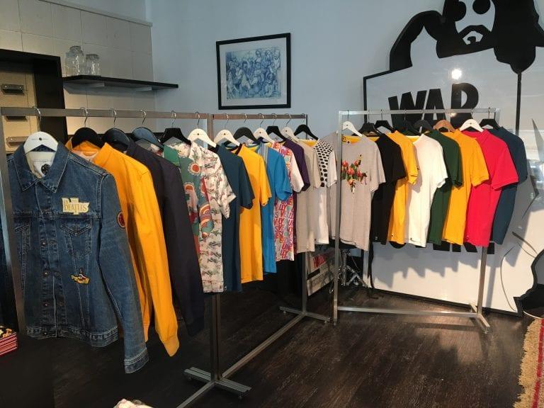 A collection of shirts and jackets hanging on two clothes rails in a gallery space.