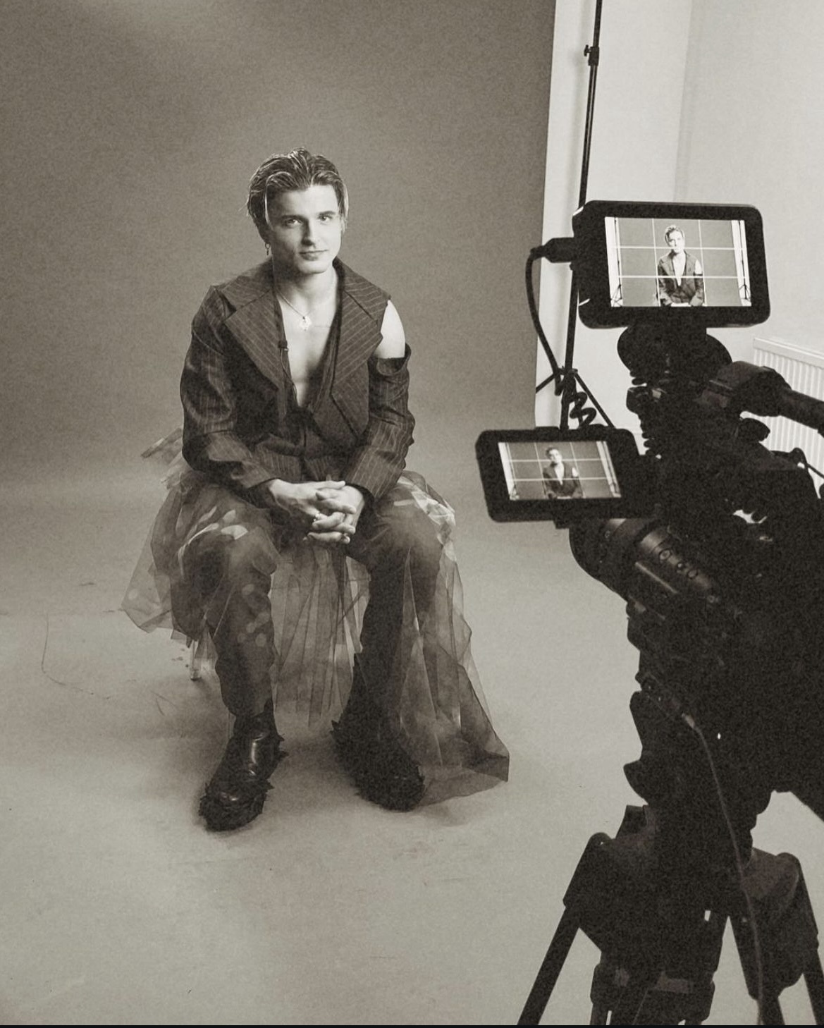 Behind-the-scenes shot of dancer N Kuzmin sitting and posing for a photo with the camera visible in the foreground.