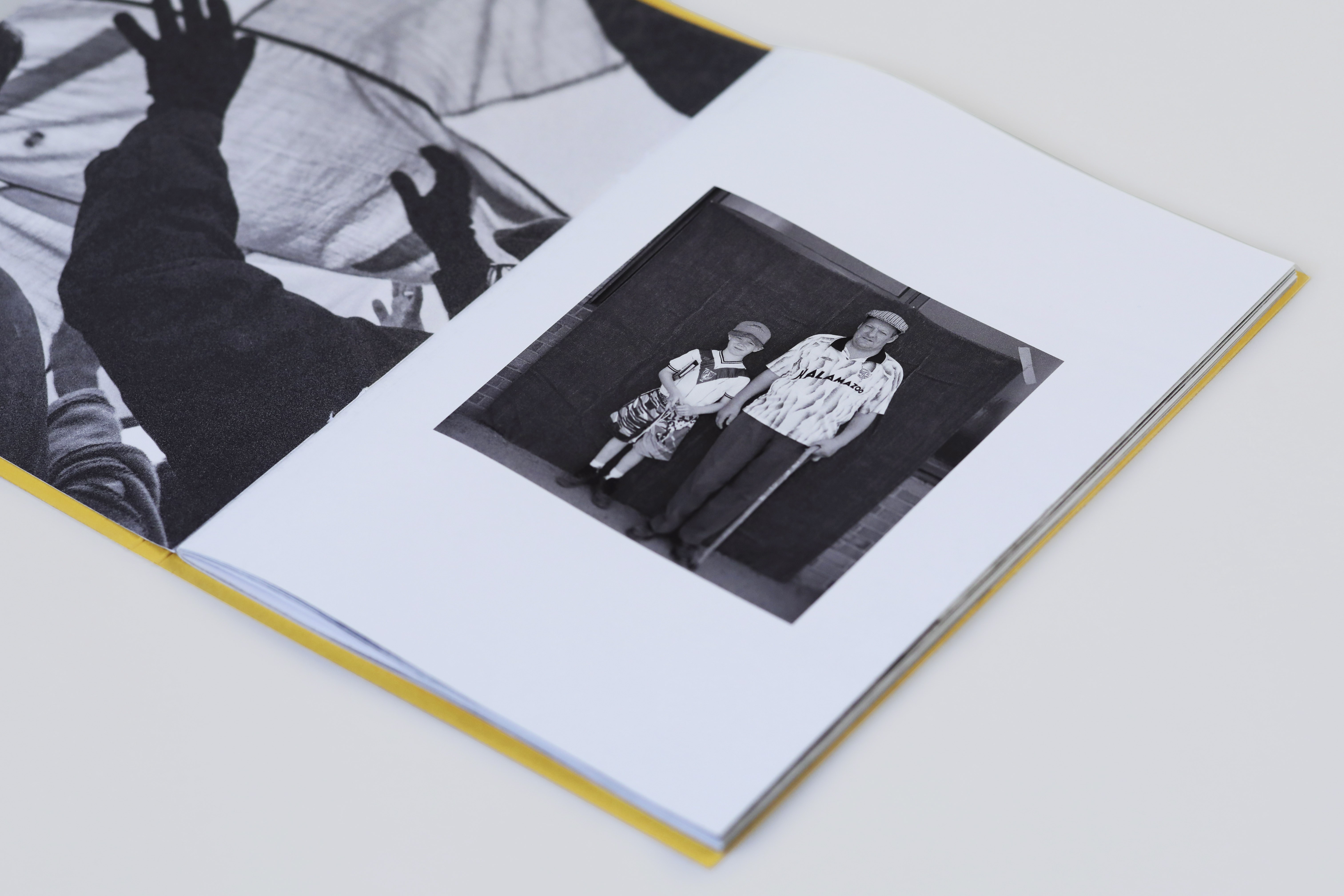 A book open to a double-page spread. The right-hand page shows a small photo of a child and an older man stood next to each other.
