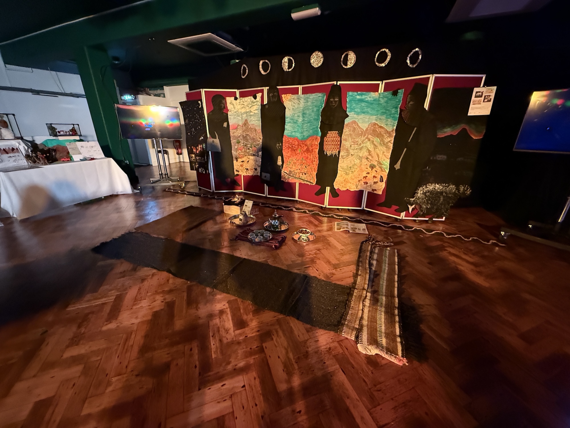 Museum interior with wooden floor, colourful geological displays in red-framed cases, dark ceiling with spotlights, white walls with exhibits.
