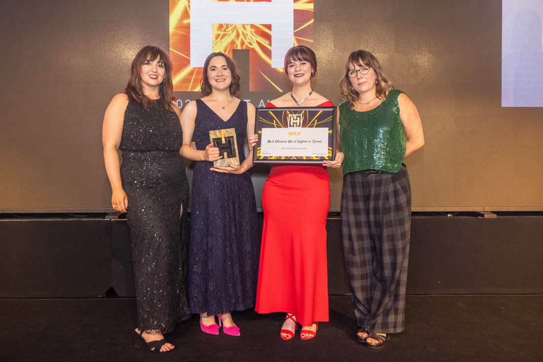 Two members of the Marketing department at AUB standing on stage accepting an award from the 2023 Heist awards.