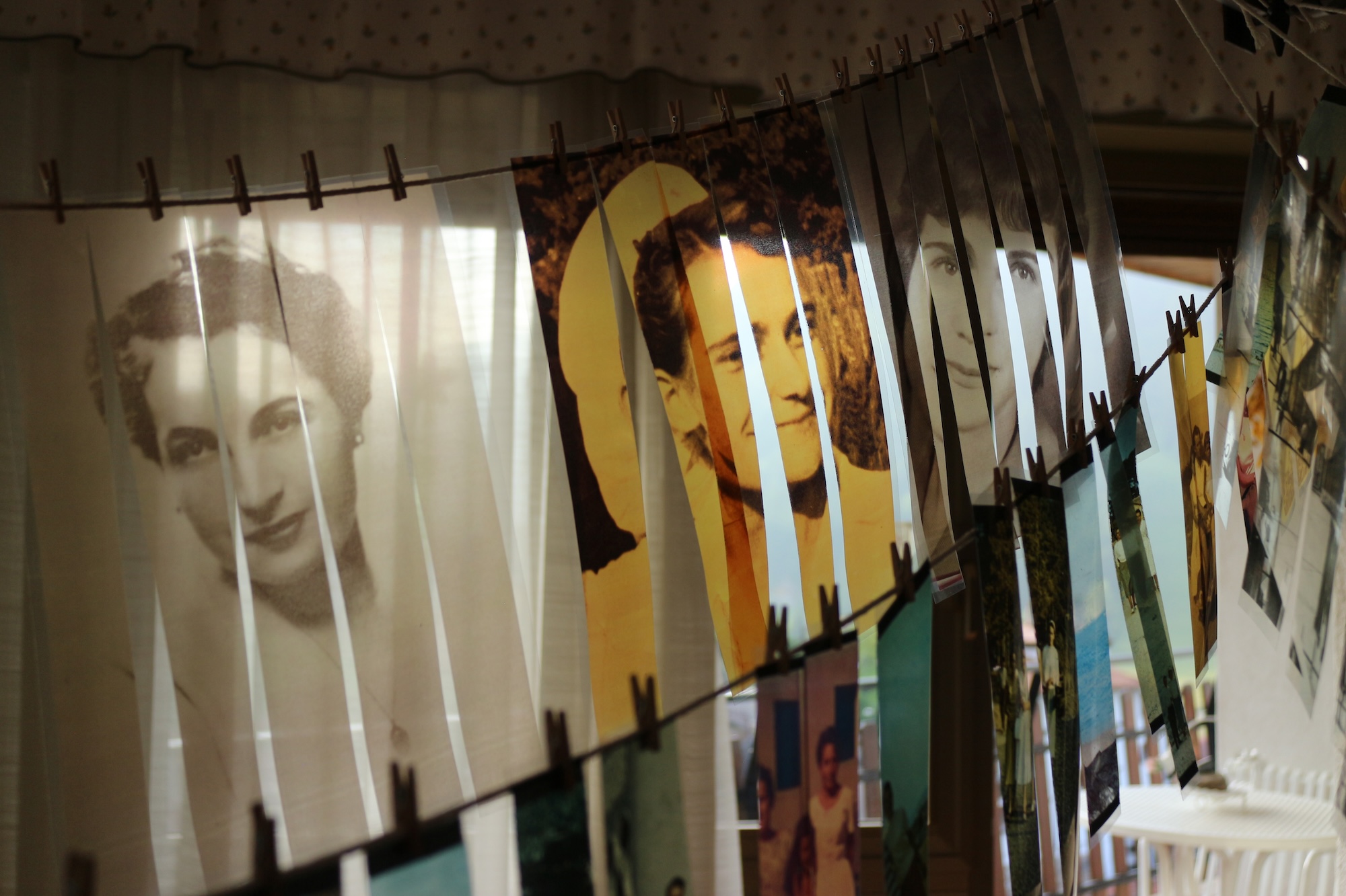Several strips comprising three black-and-white and sepia photographs drying on lines in a dark room.