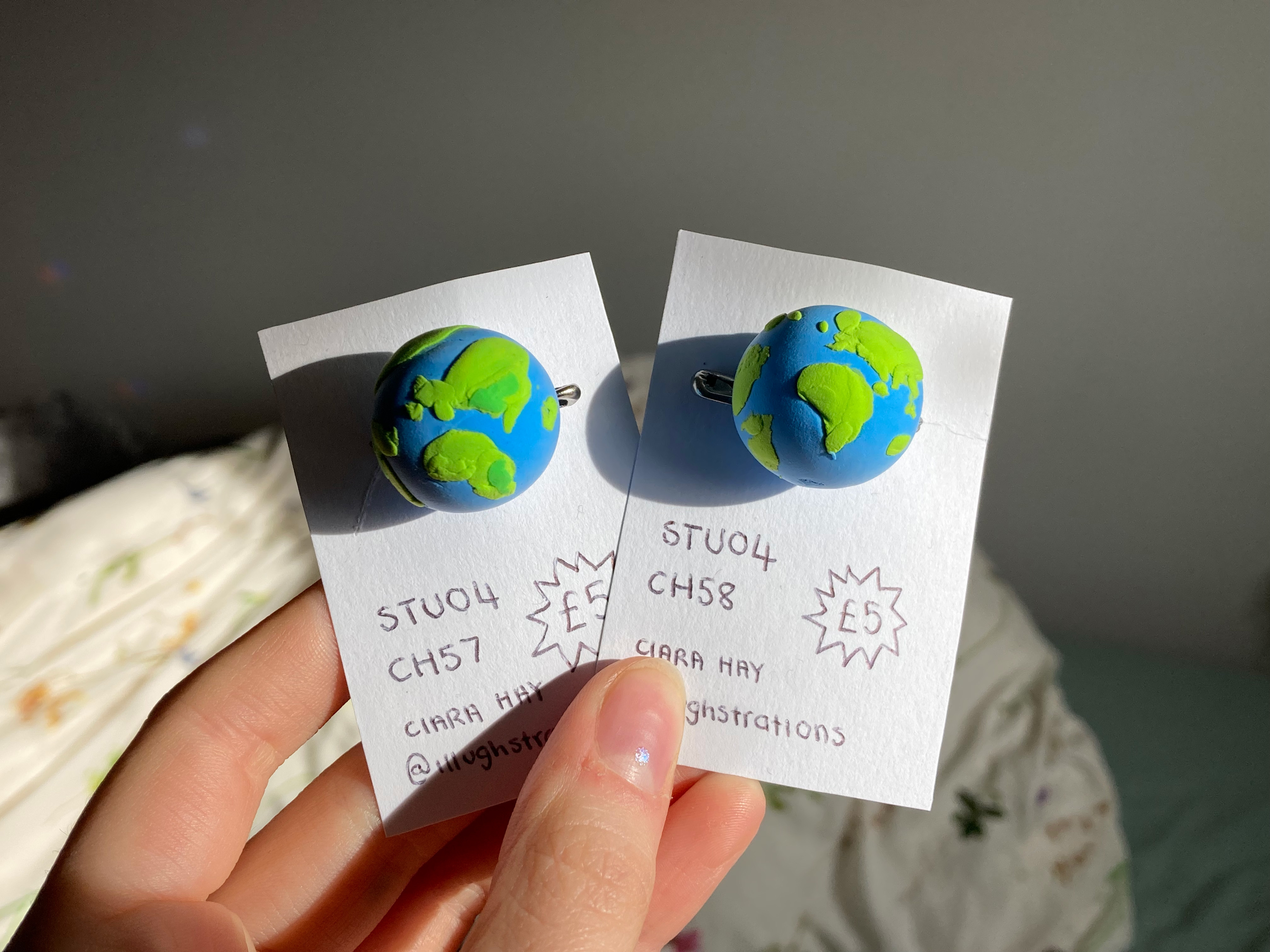 Two pin badges with handmade polymer clay world globes on them