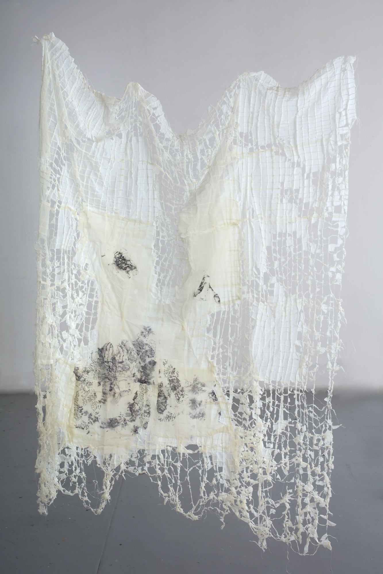 A piece of fabric looking increasingly threadbare, with an abstract drawing on part of the fabric.