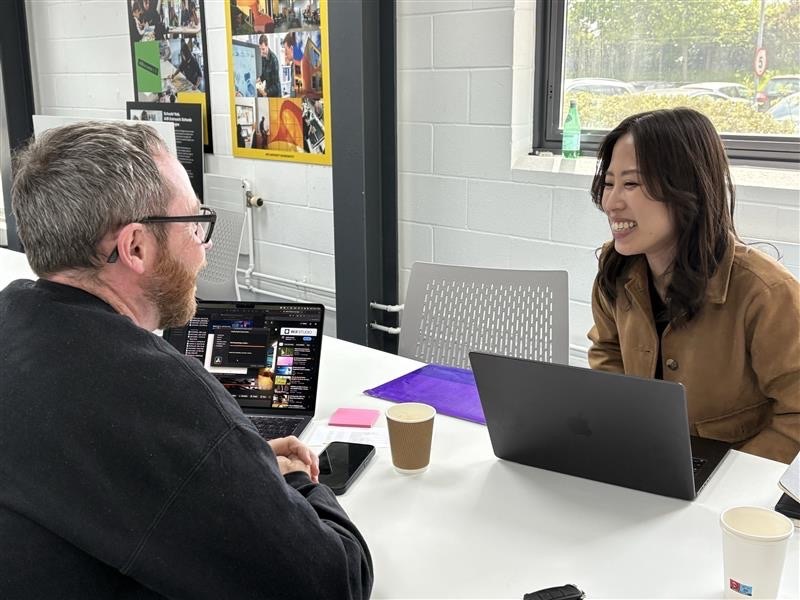 Student talking to an industry professional with a laptop in the AUB conference room.
