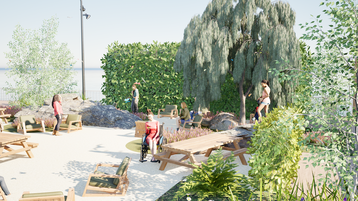 People in outdoor seating area with wooden picnic tables, large weeping willow tree, green hedging and lamp post