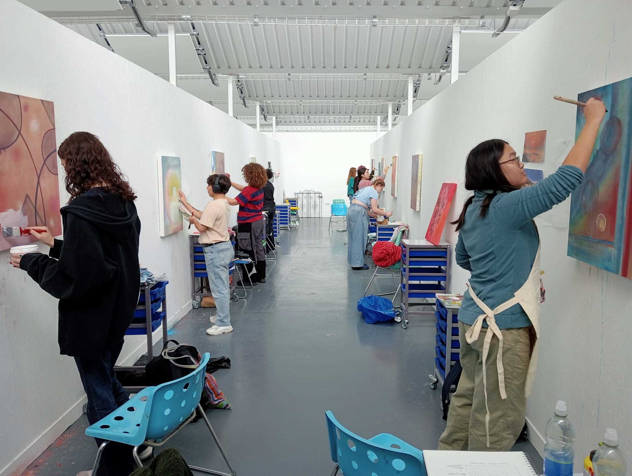 Two rows of AUB students painting on canvases inside the North Lights Studios on AUB Campus.