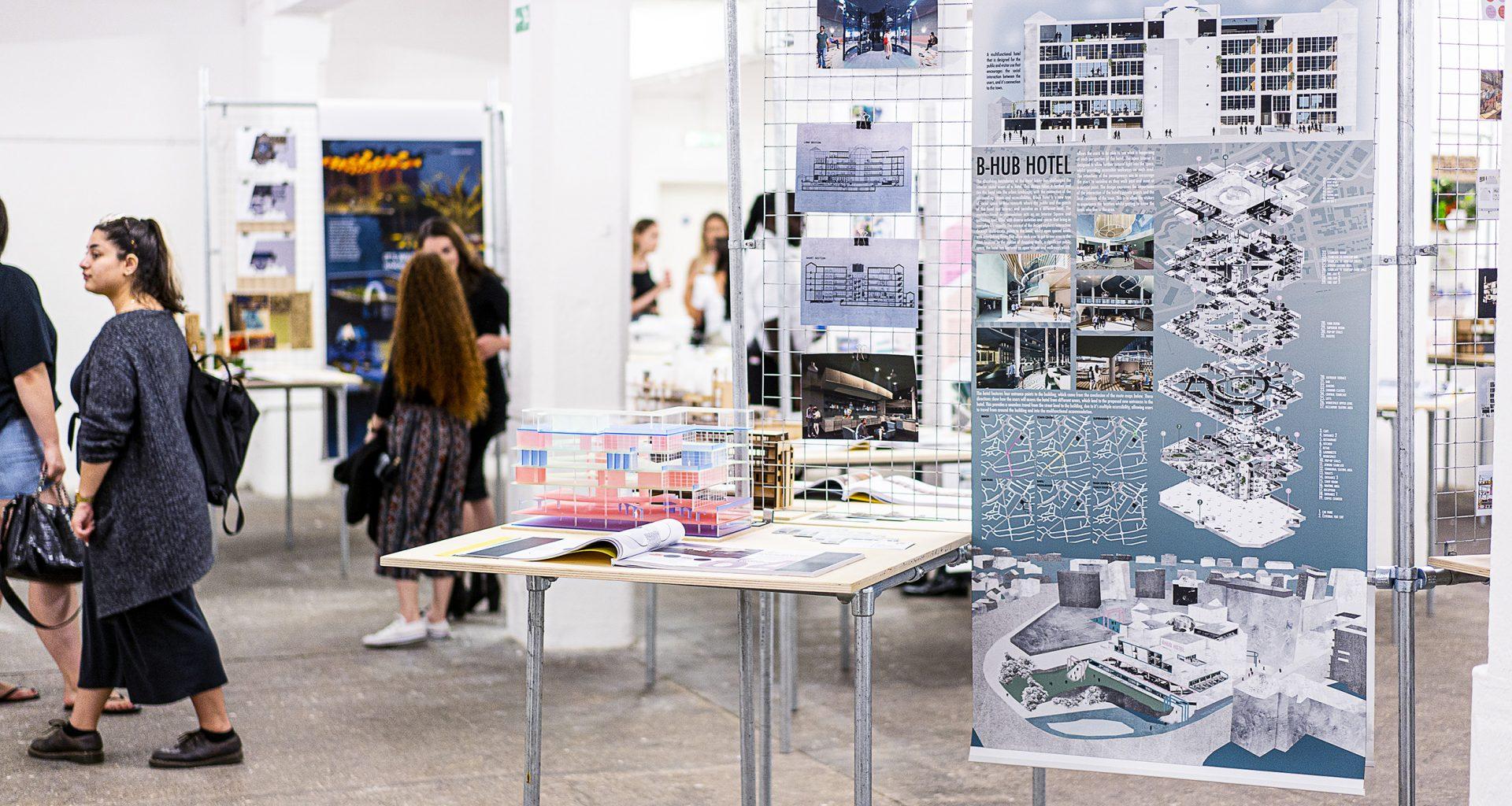 Plans and a model for a new hotel on display in a gallery space. A banner next to the display shows the vision for the hotel in more detail with diagrams, photos and blocks of text.