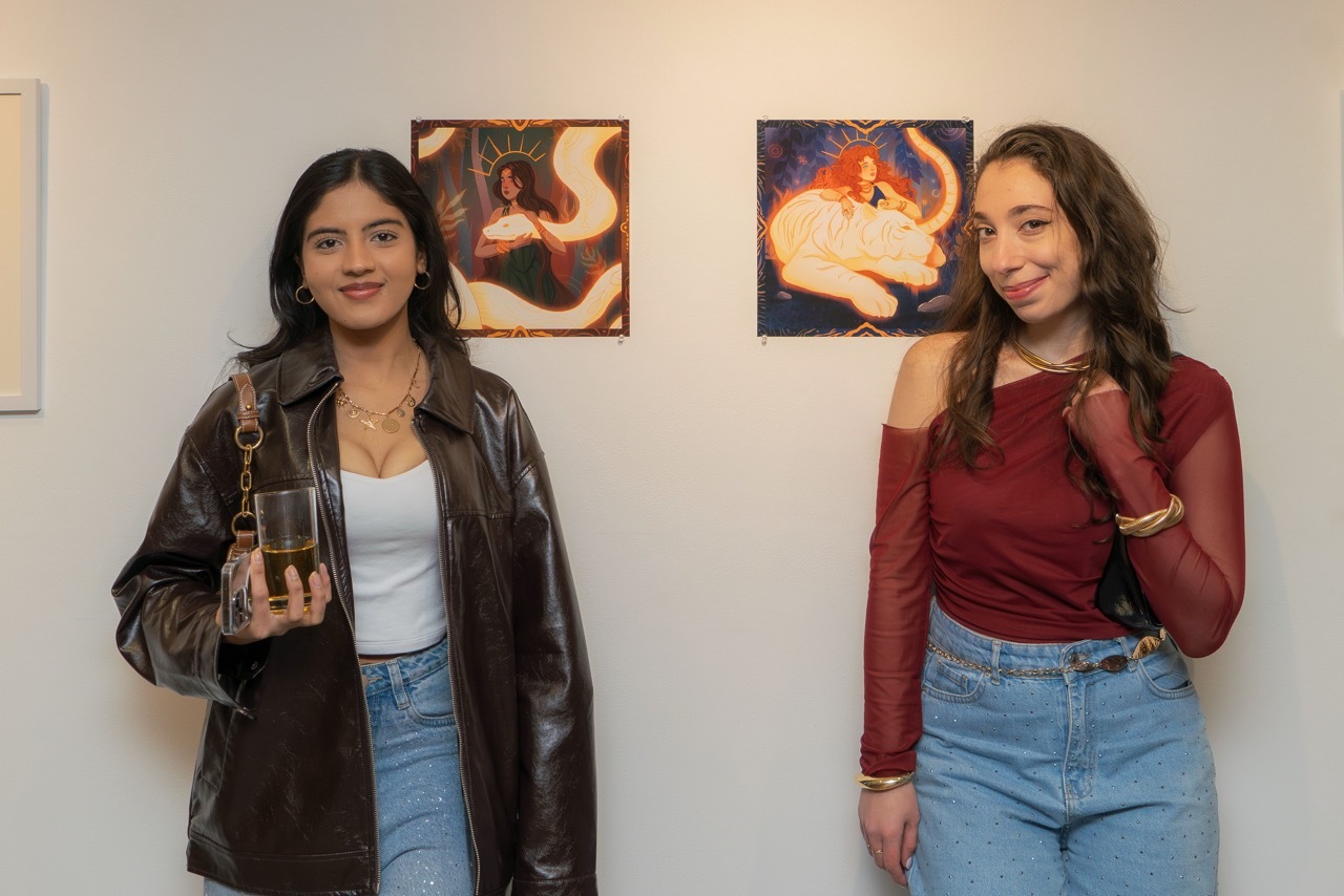 Two students stood by their artwork, both illustrated people with glowing, illuminated snake and tiger.