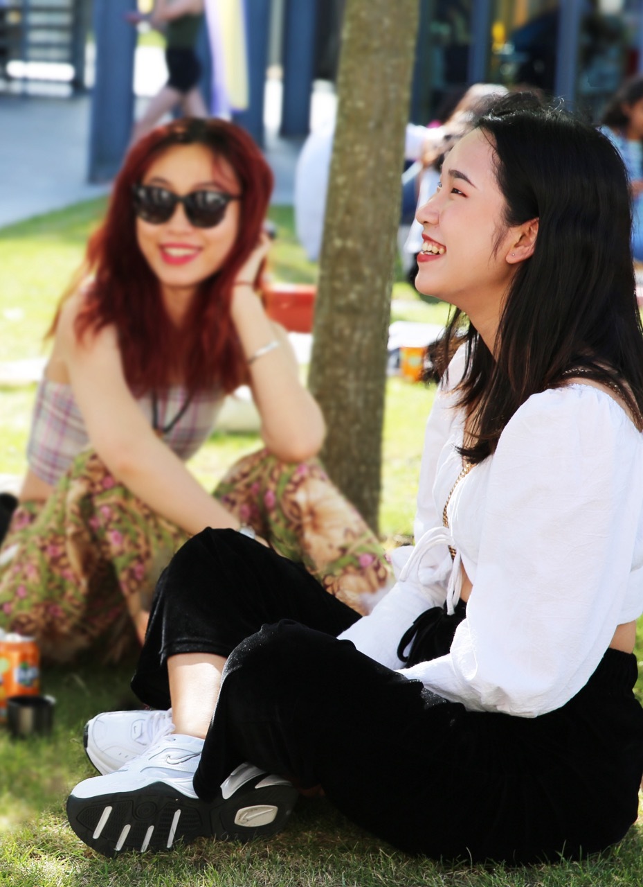 Two students sat outside by a tree on AUB campus.