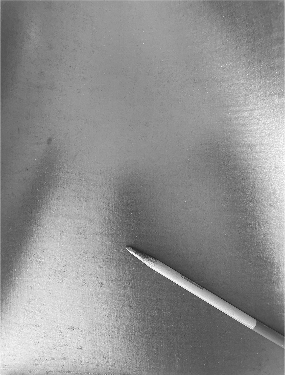 Single white knife blade positioned diagonally in bottom right corner against grey metallic surface with vertical brushed texture.
