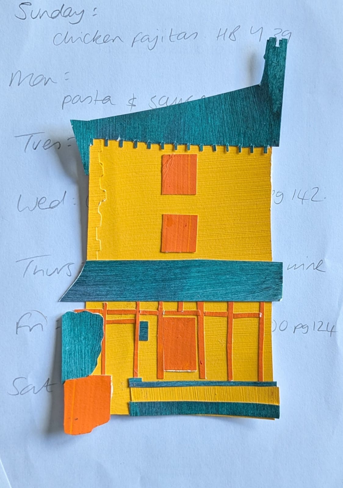 A house made up of pieces of coloured paper, lying on a piece of white paper with a handwritten meal plan on it.