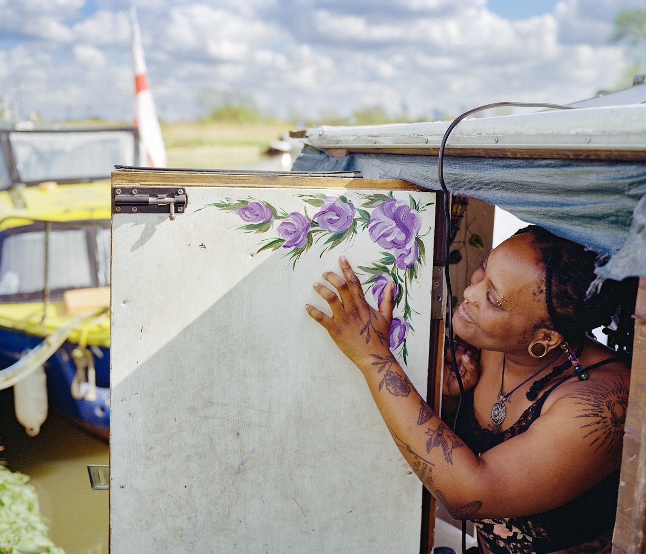 Person looking to the side of boat. Their hand touches the outside of boat with floral pattern painted.