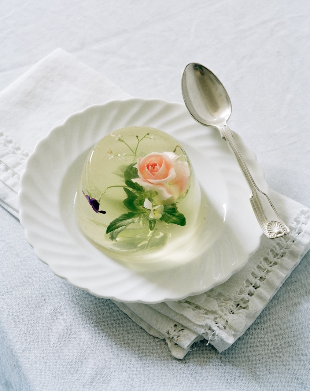 Clear, floral jelly on a white plate with a spoon.