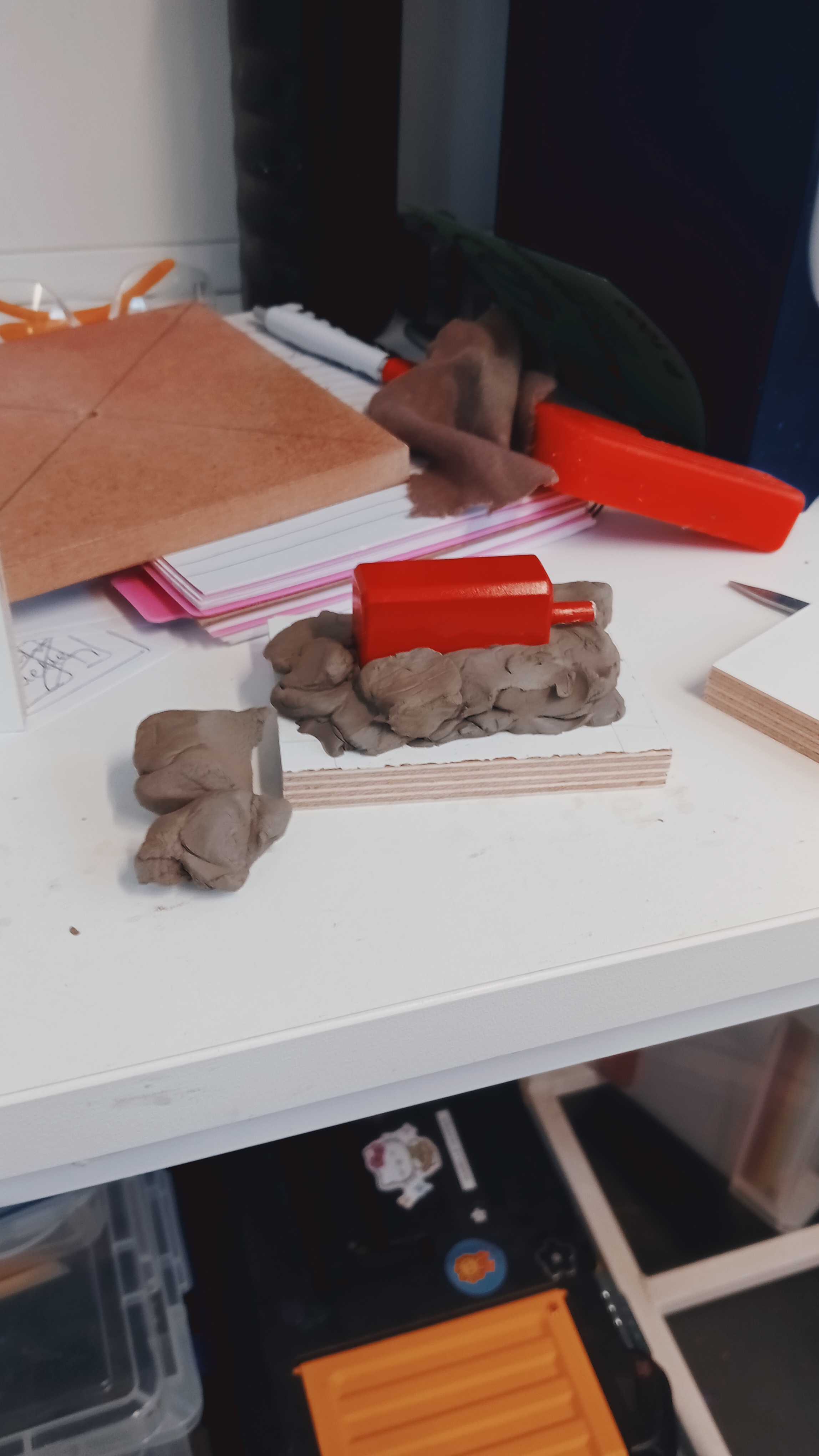 Clay mould holding a red object on a table.