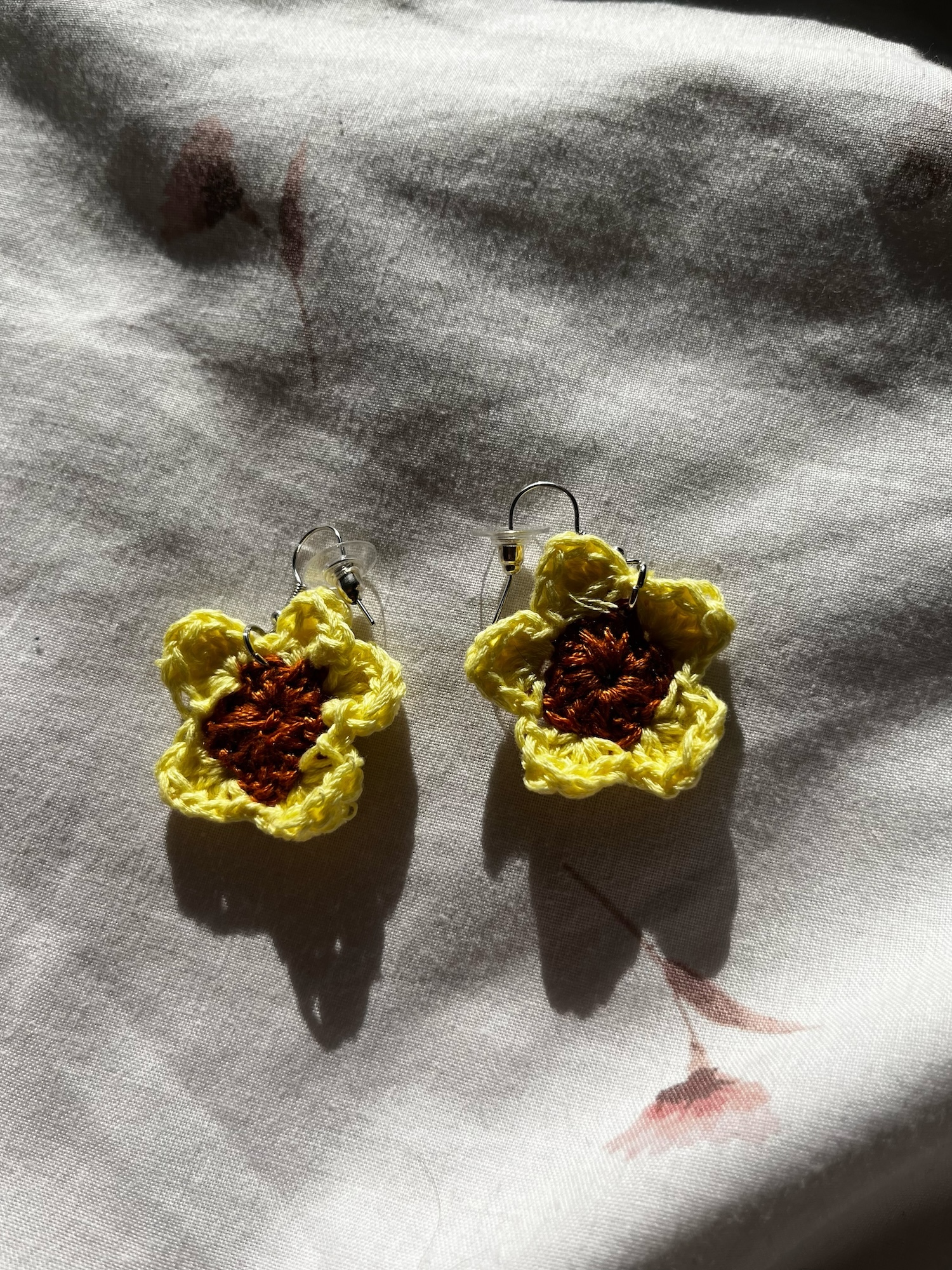 A pair of earrings with a yellow crochet design.