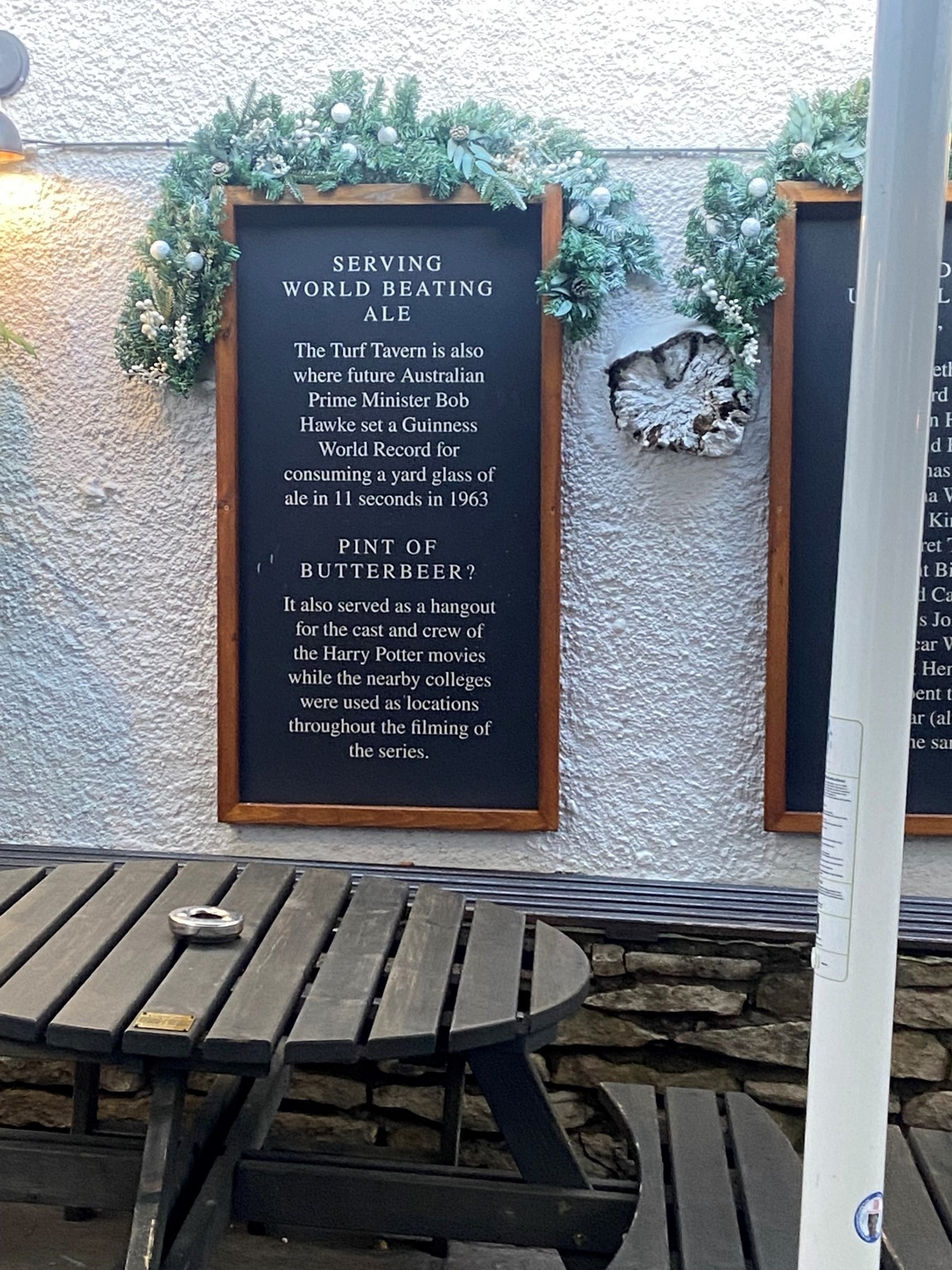 A sign outside a pub with text reading, "The Turf Tavern is also where future Australian Prime Minister Bob Hawke set a Guinness World Record for consuming a yard glass of ale in 11 seconds in 1963. It also served as a hangout for the cast and crew of the Harry Potter movies while the nearby colleges were used as locations throughout the filming of the series."