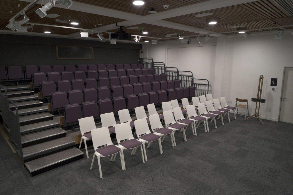 Rows of seats and a set of steps in an empty lecture theatre.