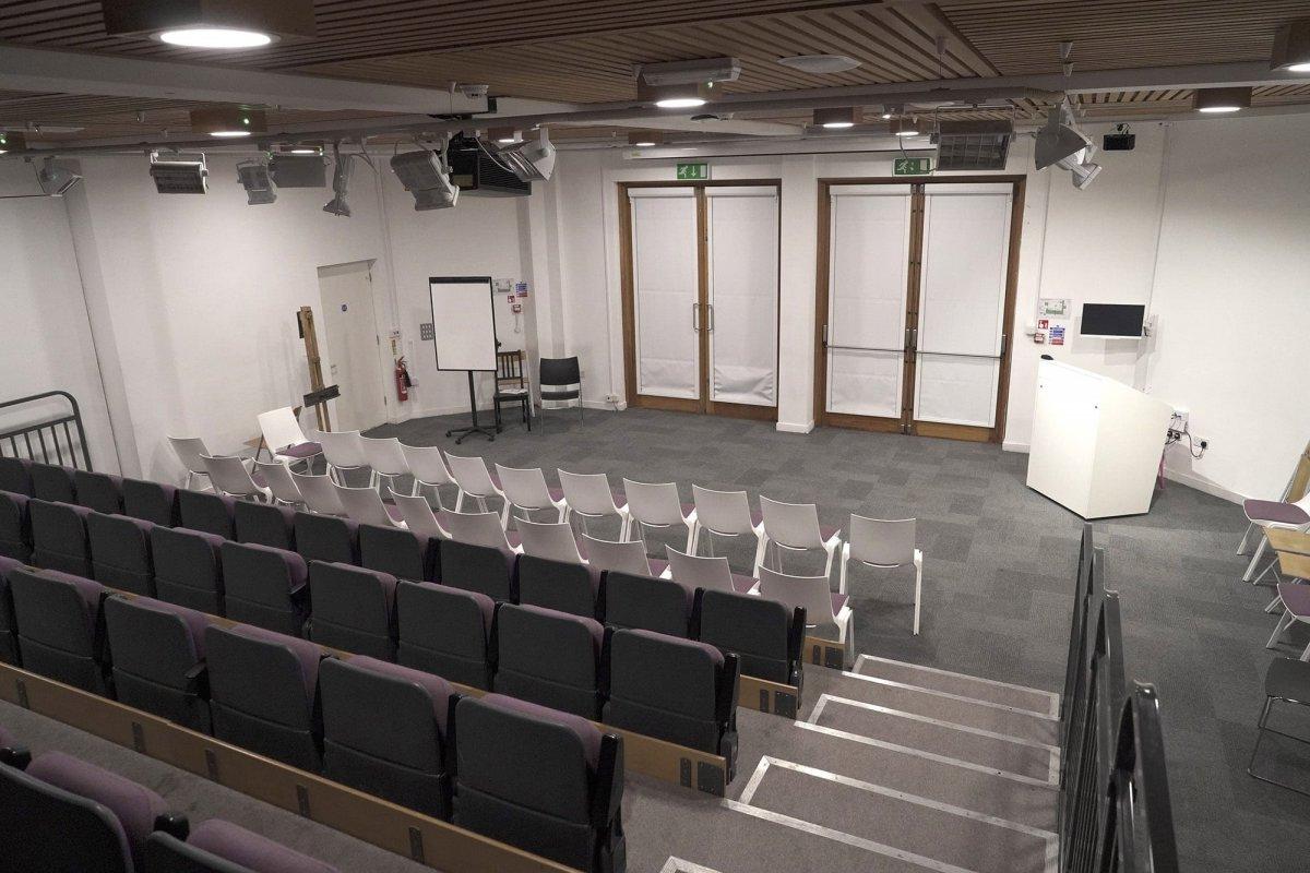 Empty lecture theatre viewed from the top of a set of steps next to rows of seating.