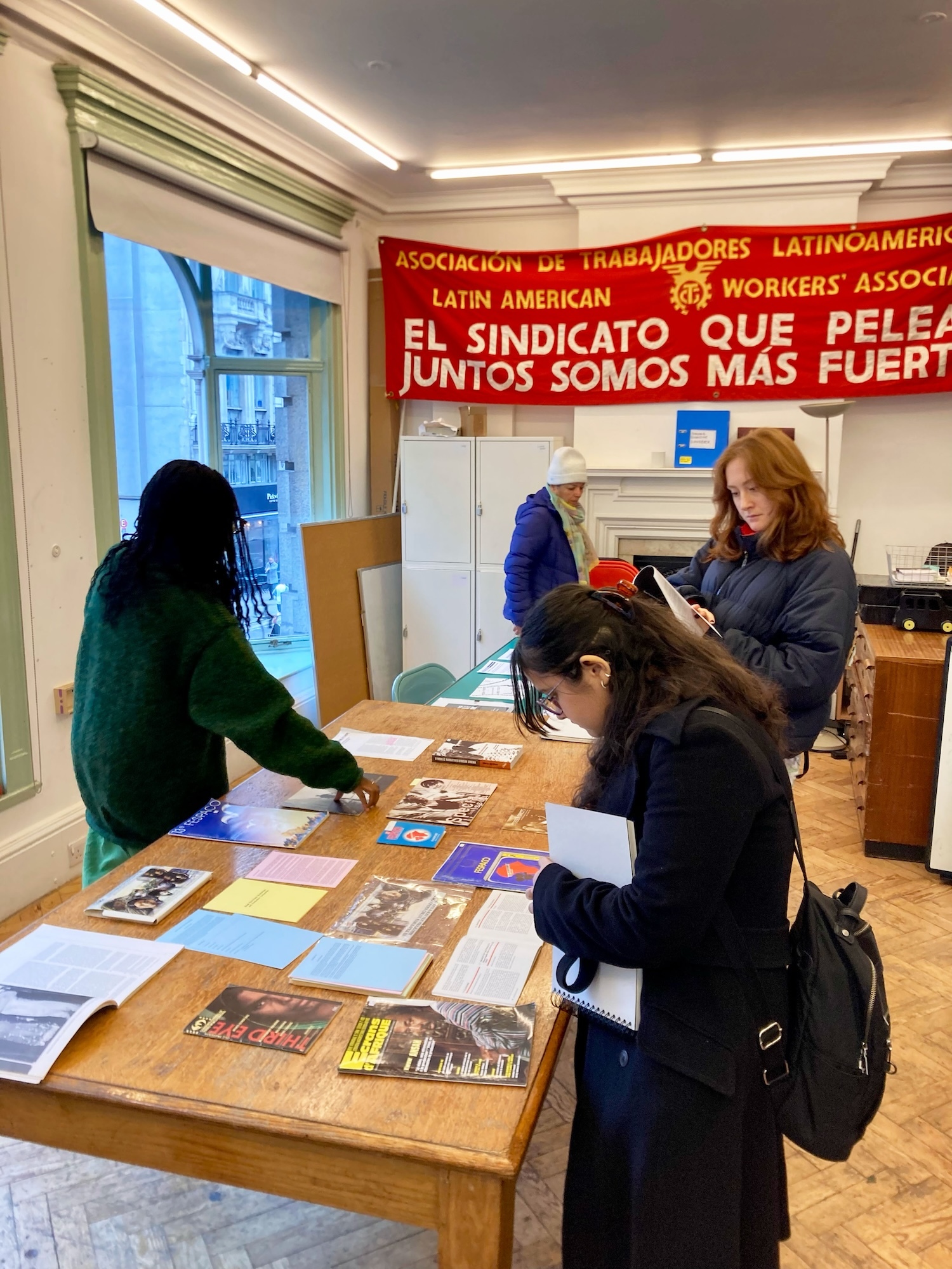 Four people gathered around a table at the June Givanni Pan African Film Archive looking at documents.
