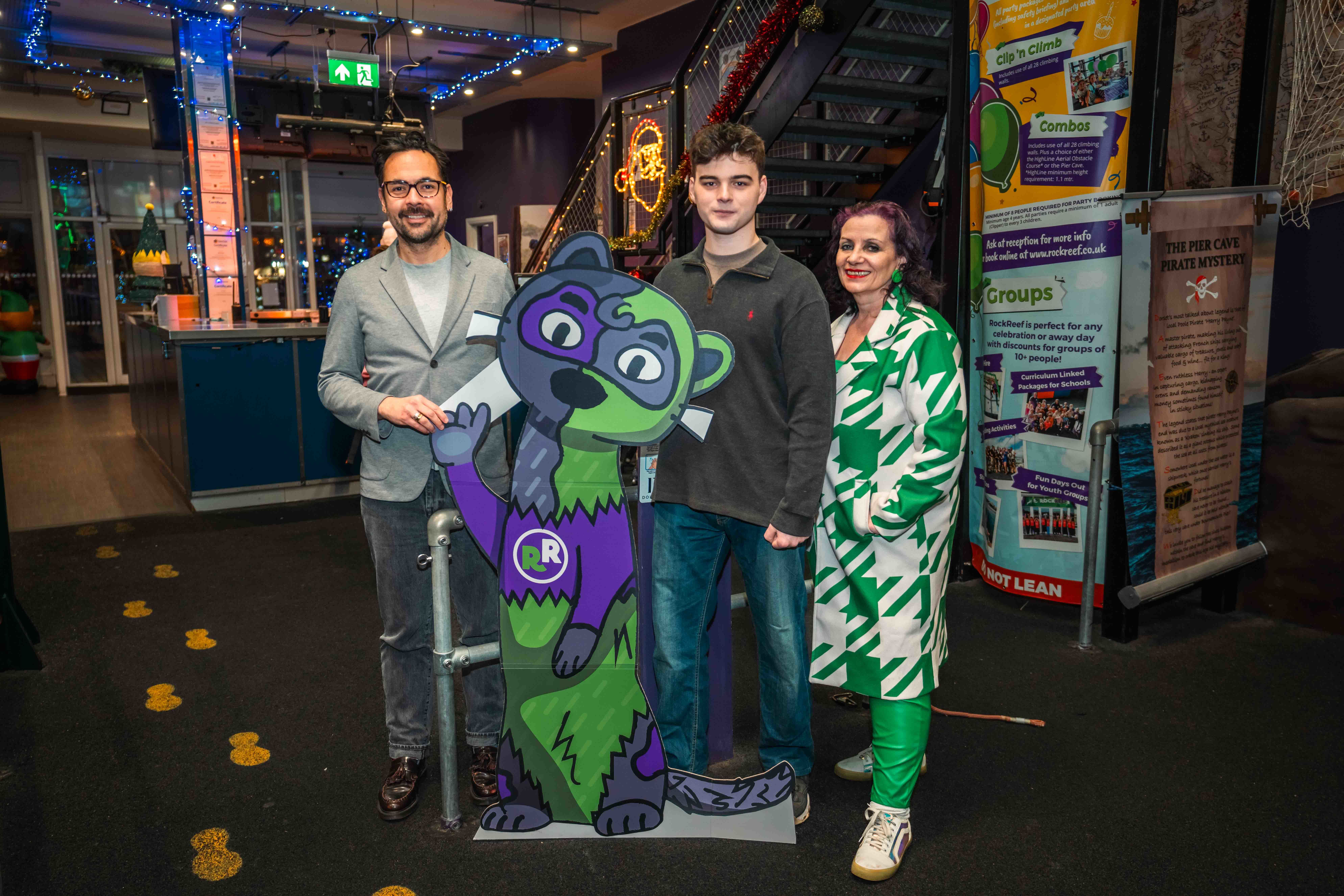 J Balcazar, B Roberts and V. M. McClean standing next to a cutout of a green and purple otter.