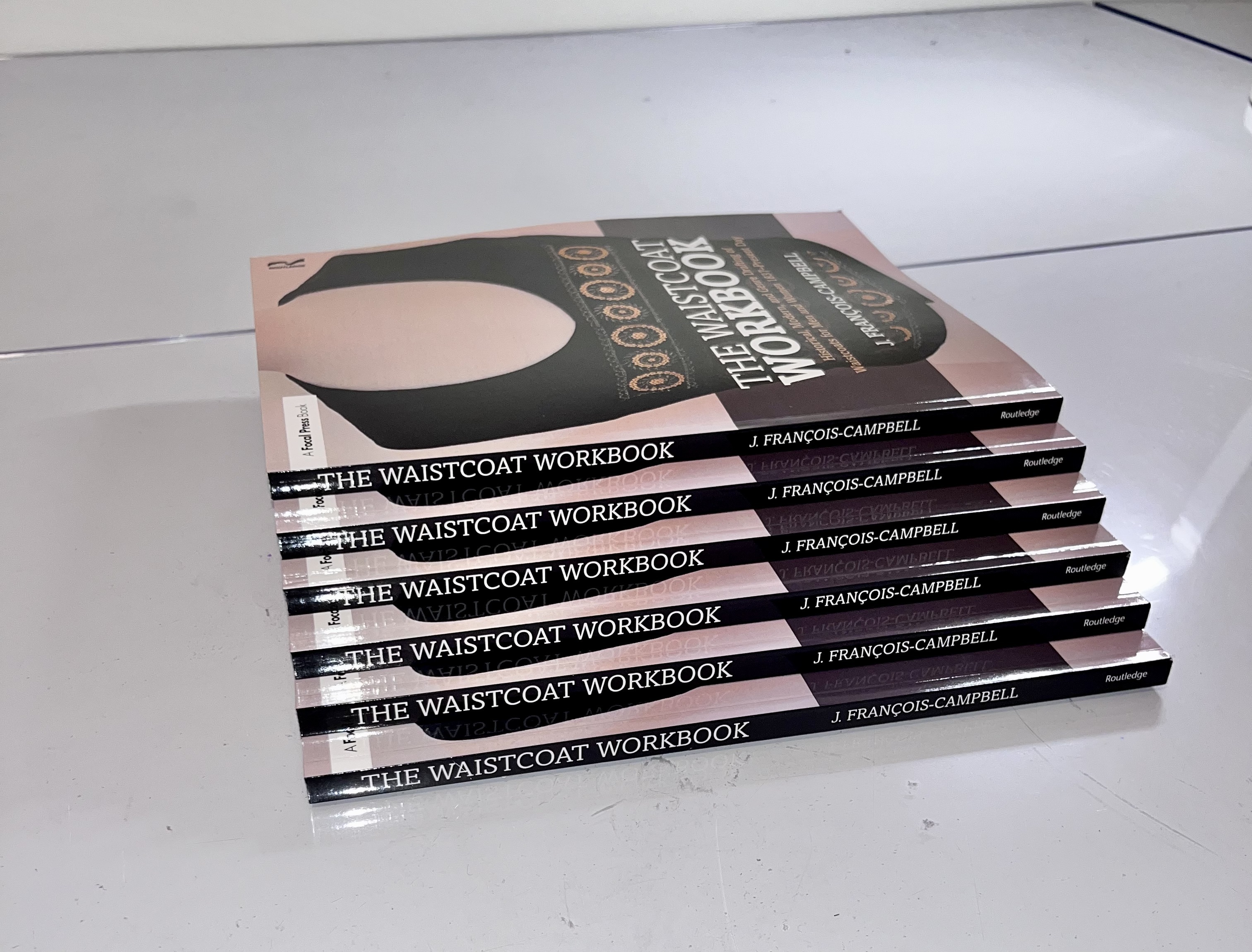 Several stacked copies of "The Waistcoat Workbook" by Jay François-Campbell.