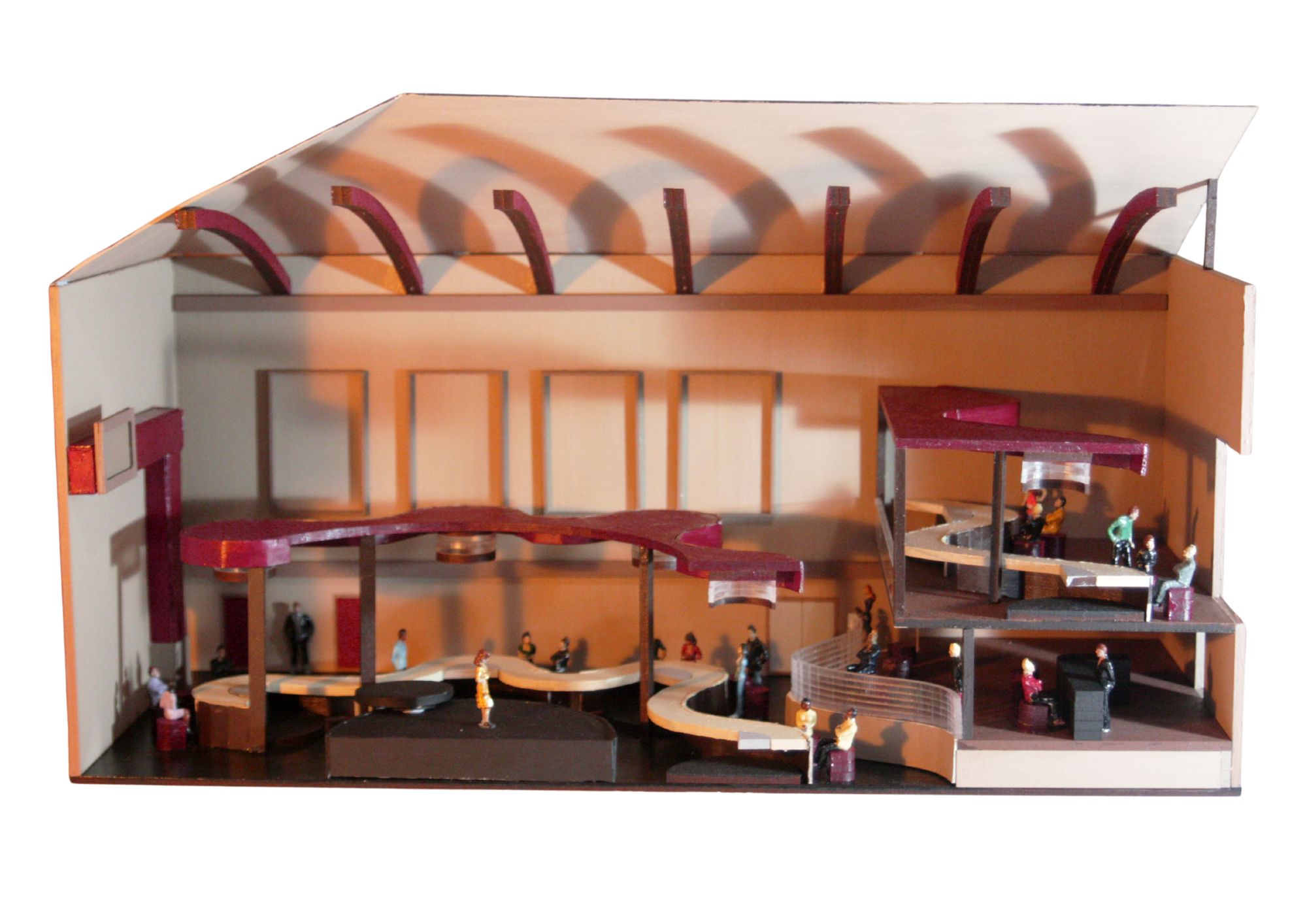 A detailed architectural model of a theatre, featuring multiple levels with seating areas, a stage, and small figurines representing people. The model includes curved pathways and structural elements in warm tones, showcasing the interior design.