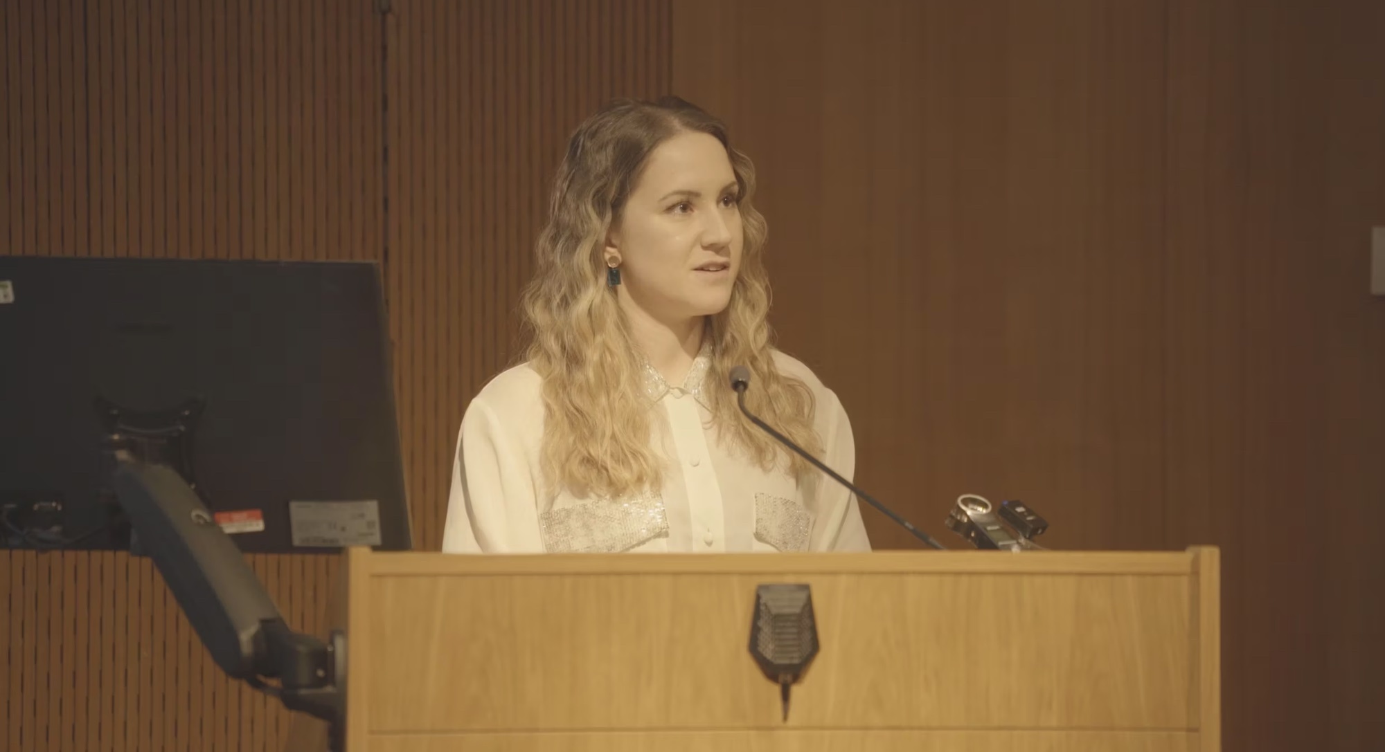 BA (Hons) Costume alumna J Hawkes standing at a lectern giving a talk at an AUB Open Day.