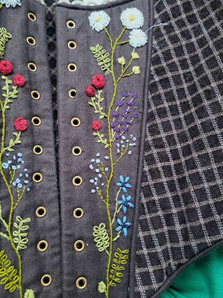Close up of the hand embroidering, using the language of flowers each of these represents hope, love, unity and peace.