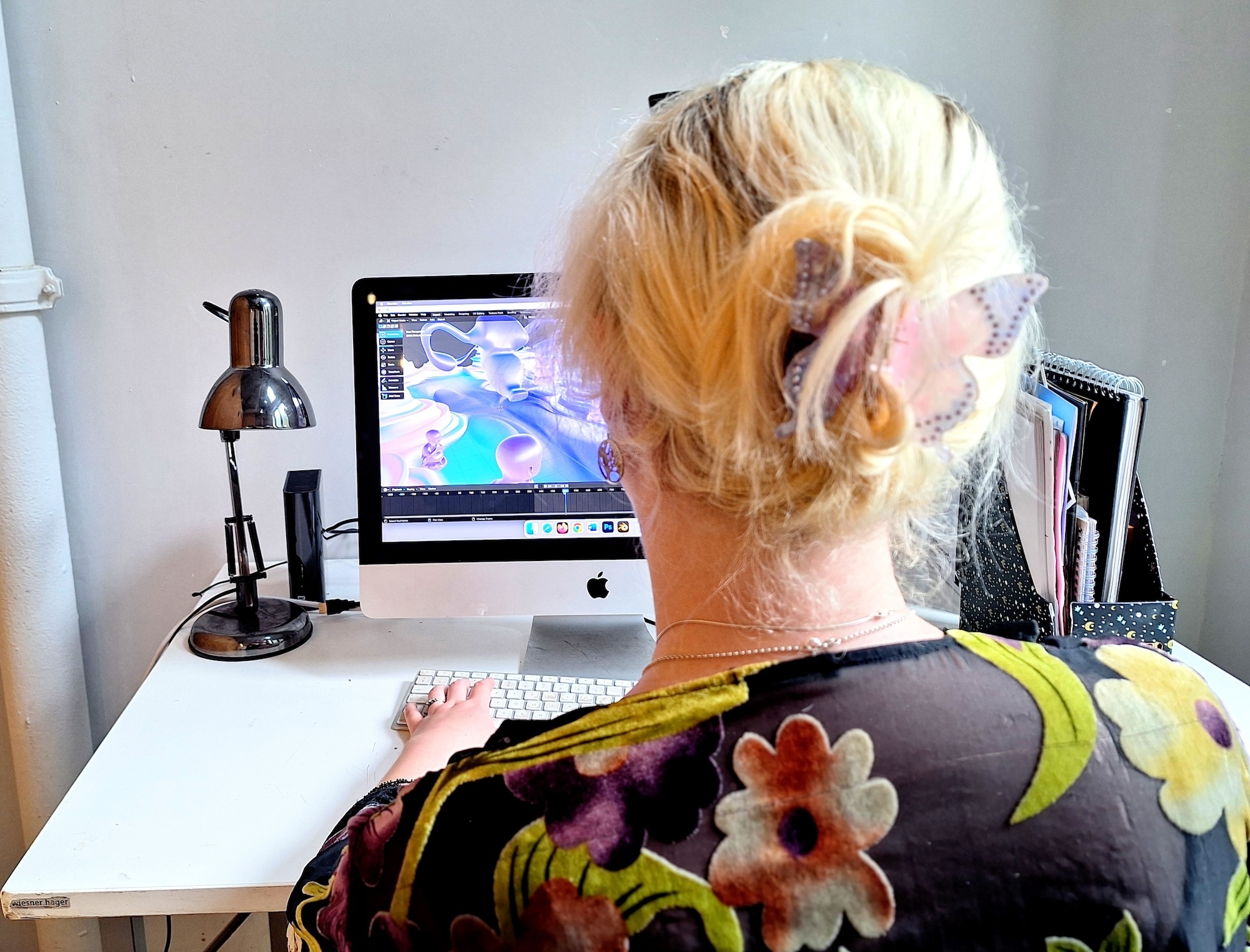 Jessica Tipper working on a Mac with 3D design, shot from behind.